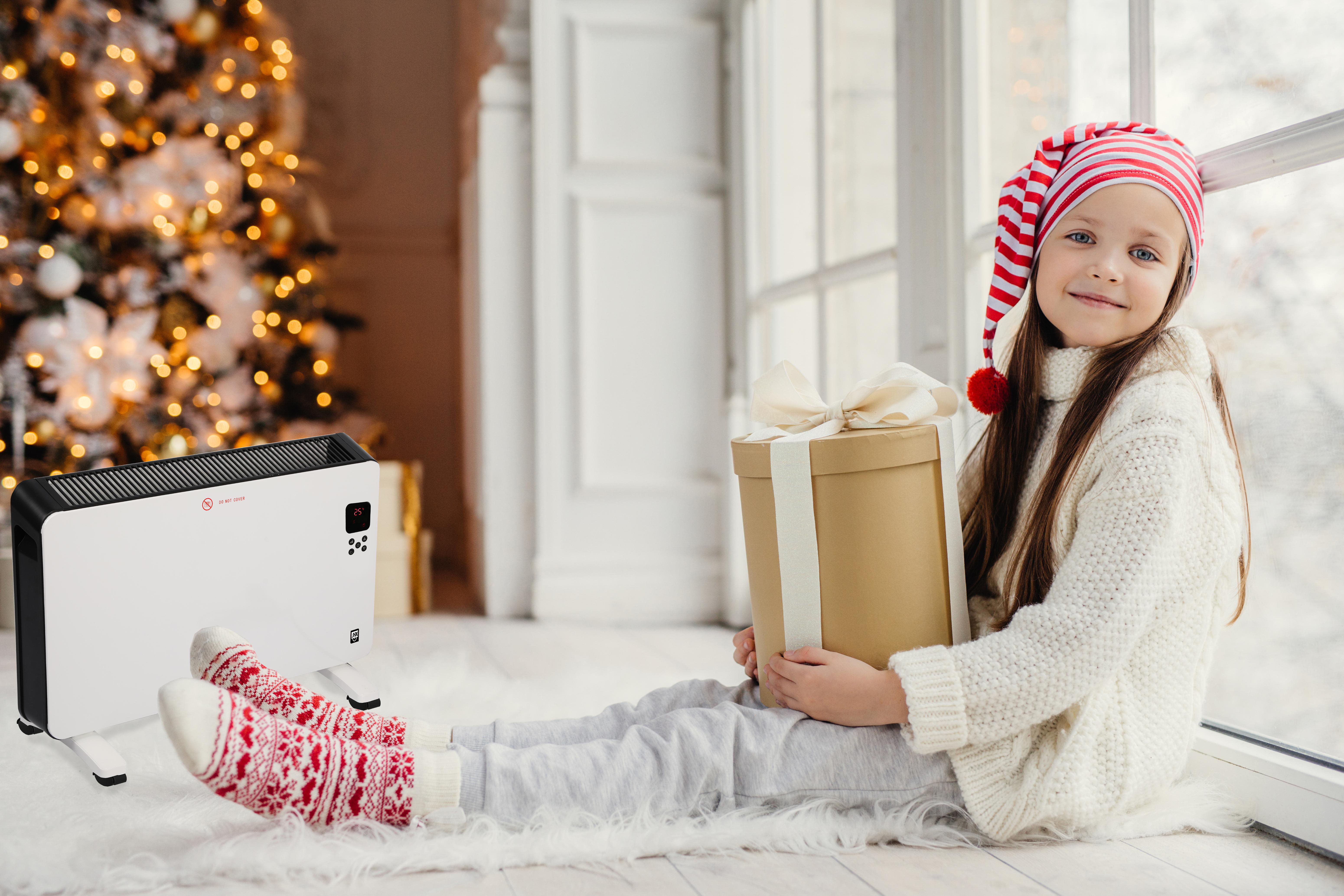 Mädchen mit Geschenk und Heizung vor Weihnachtsbaum