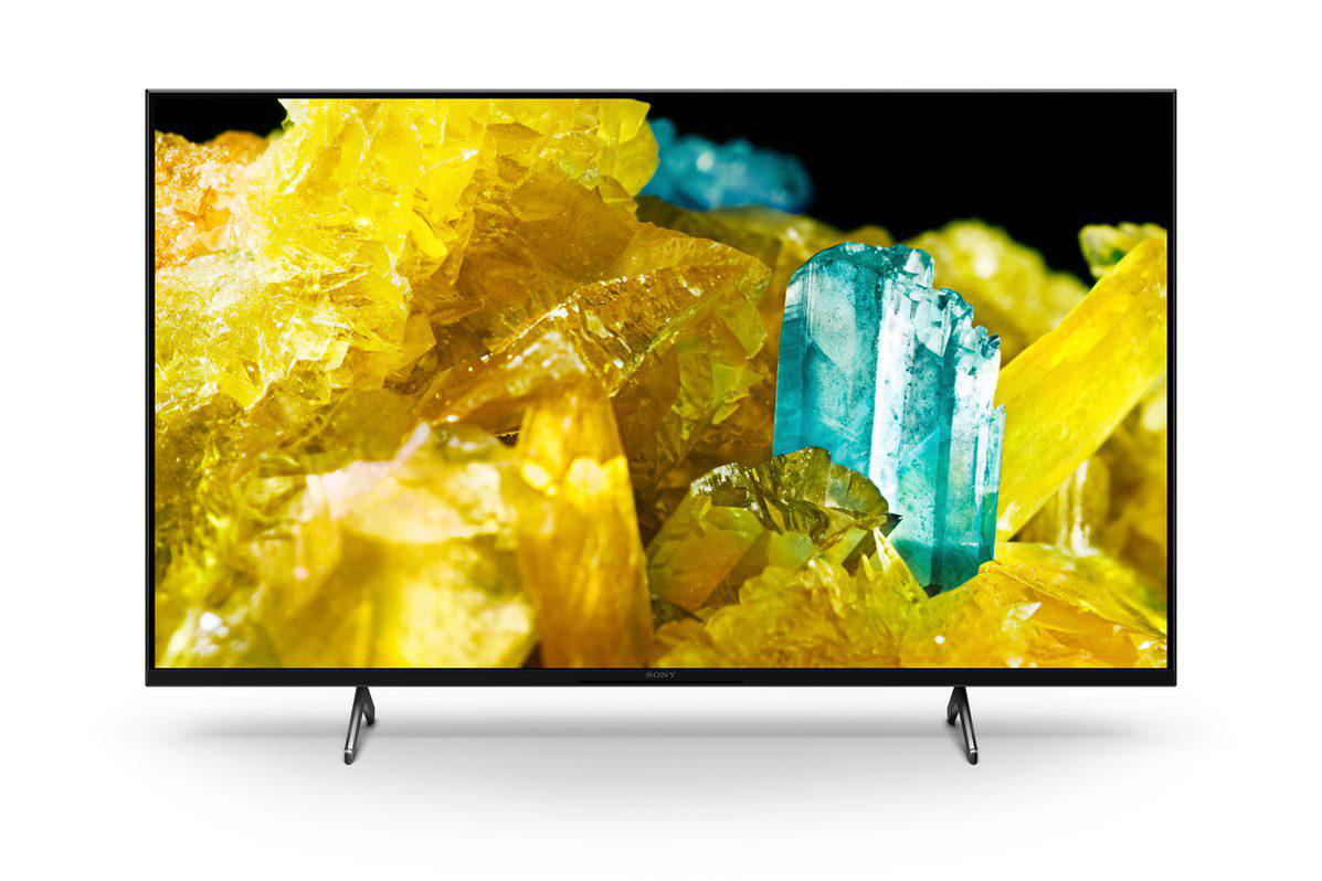 Ein Fernsehbildschirm mit bunten Kristallen, gelb und blau. Der Fernseher steht auf weißem Grund mit schwarzem Ständer.
