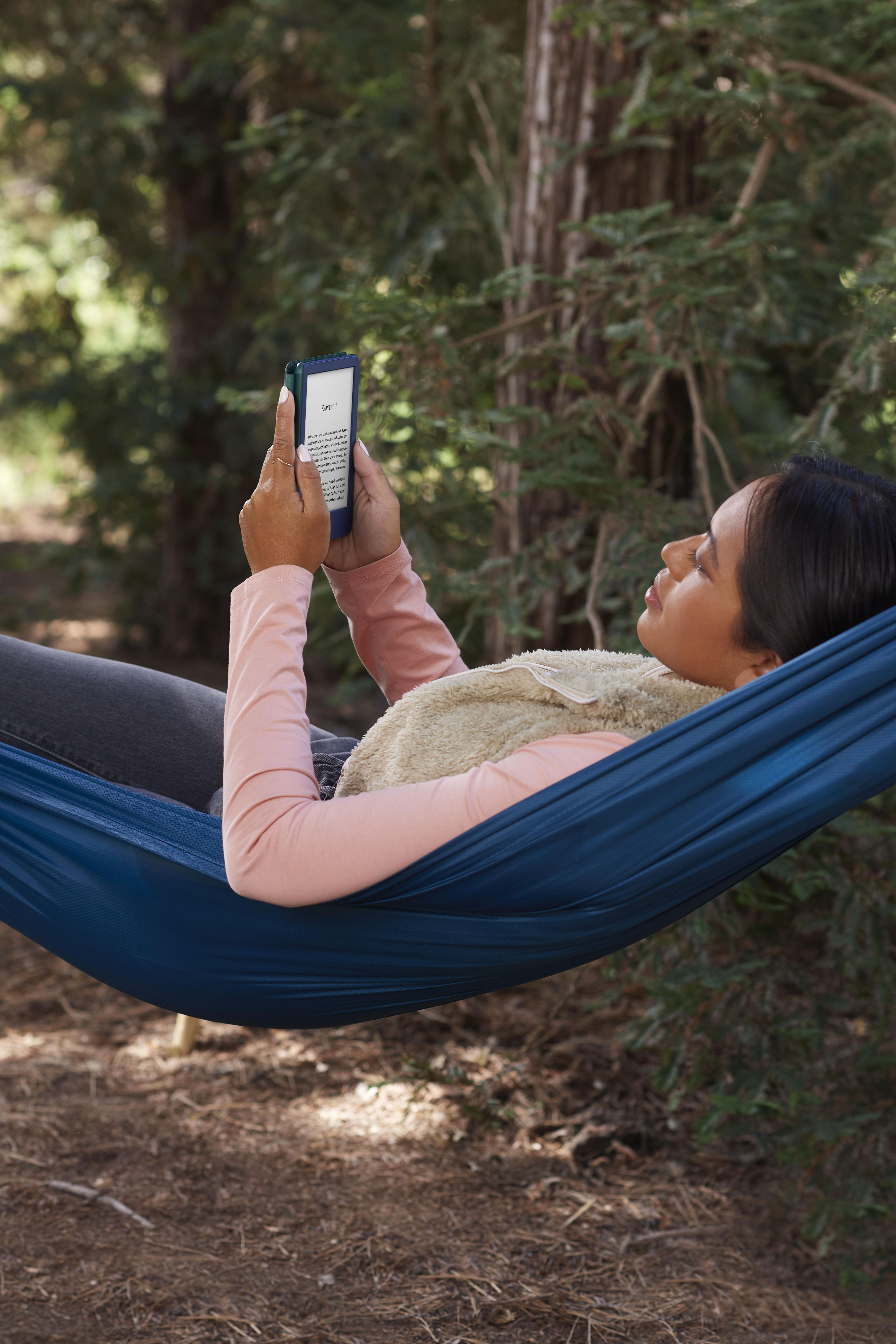 Frau liest E-Book in einer Hängematte im Wald.