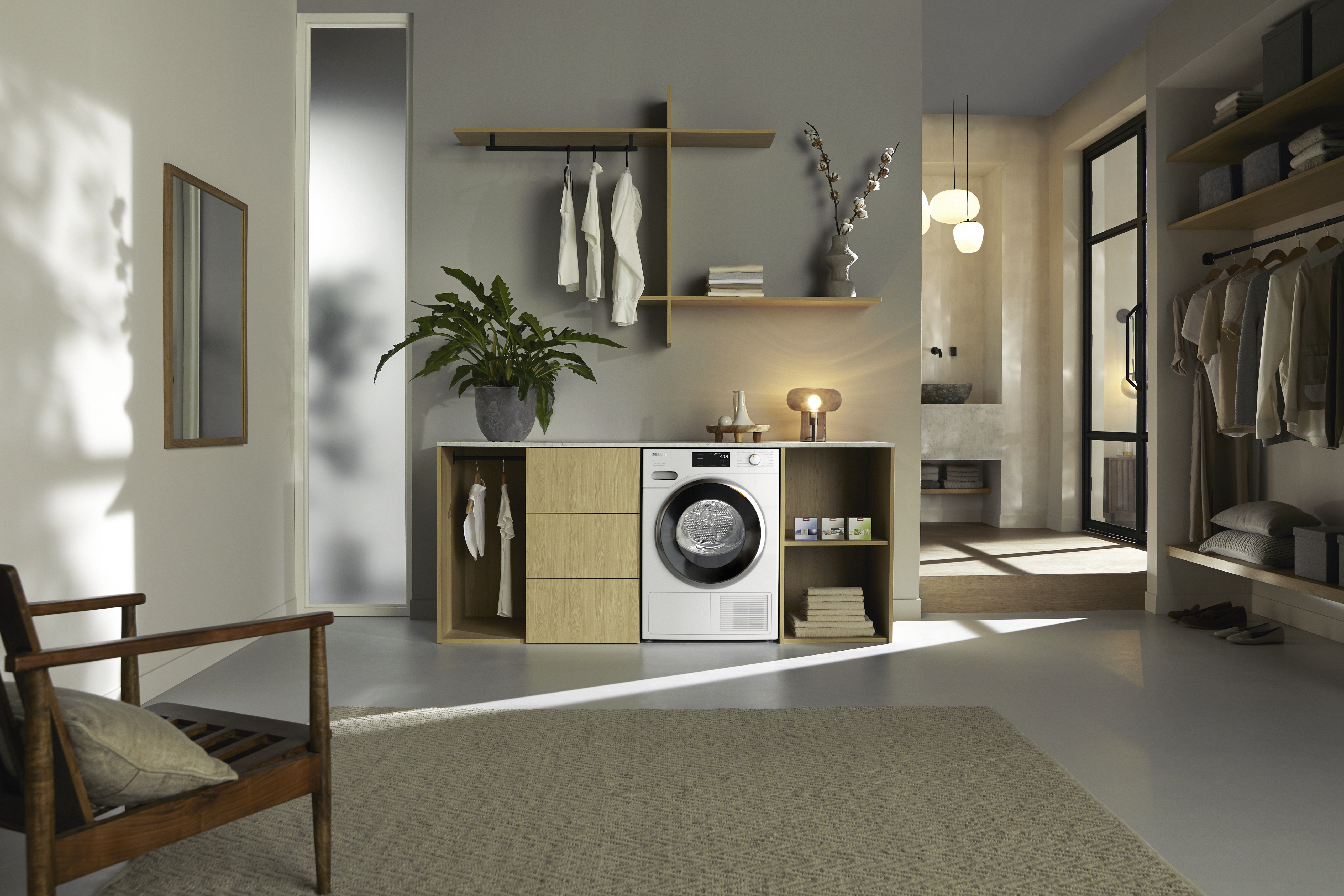 Ein moderner Waschraum mit Waschmaschine, Holzregalen, Kleidung und Teppich. In der Ecke steht ein Stuhl.