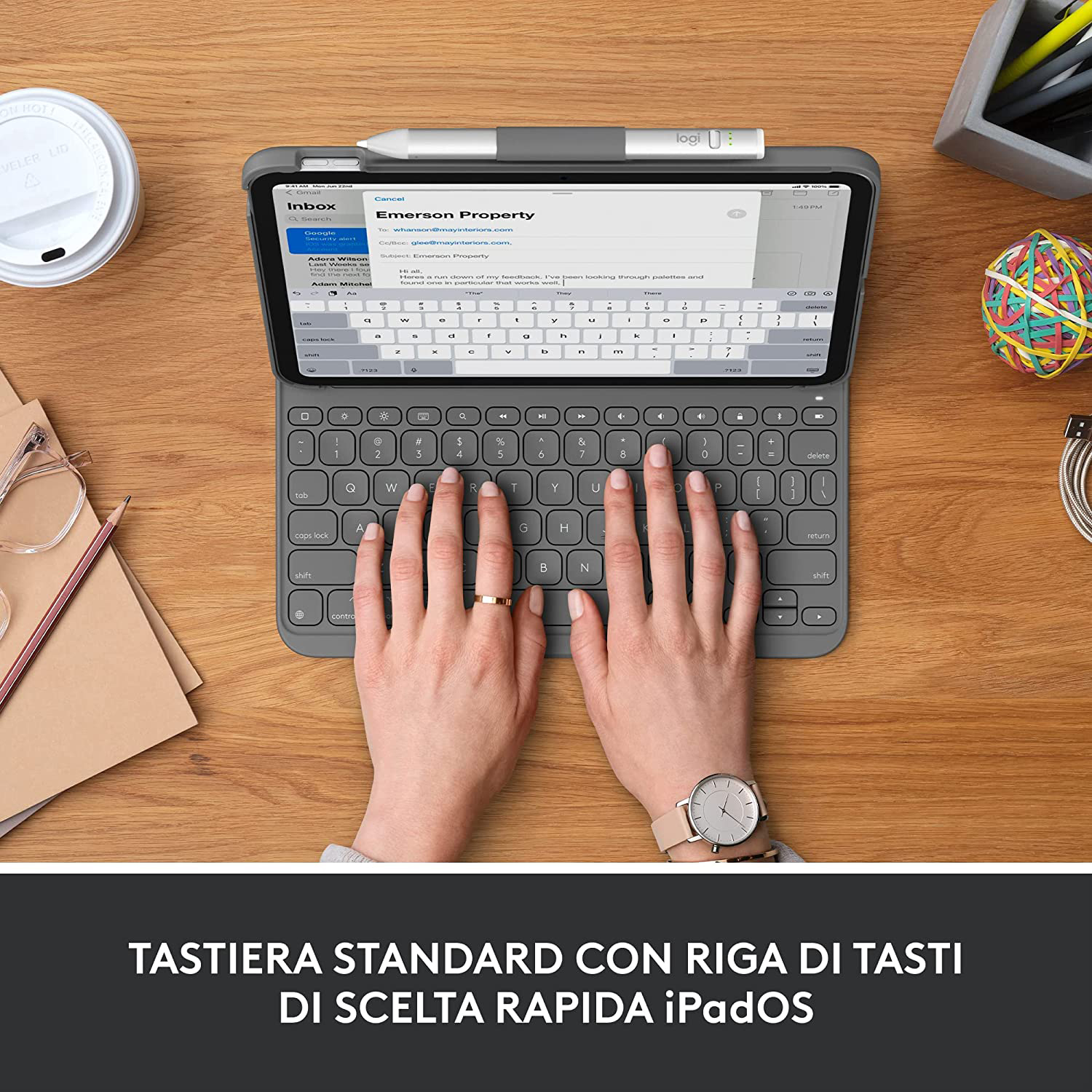 Mani di una persona su una tastiera grigia con un tablet che mostra una casella di posta elettronica.
