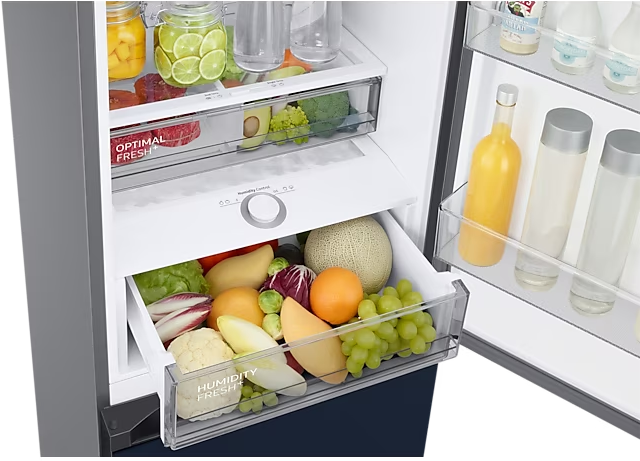Interno del frigorifero con verdure e frutta nei cassetti. Bottiglie di succo sullo scaffale della porta.