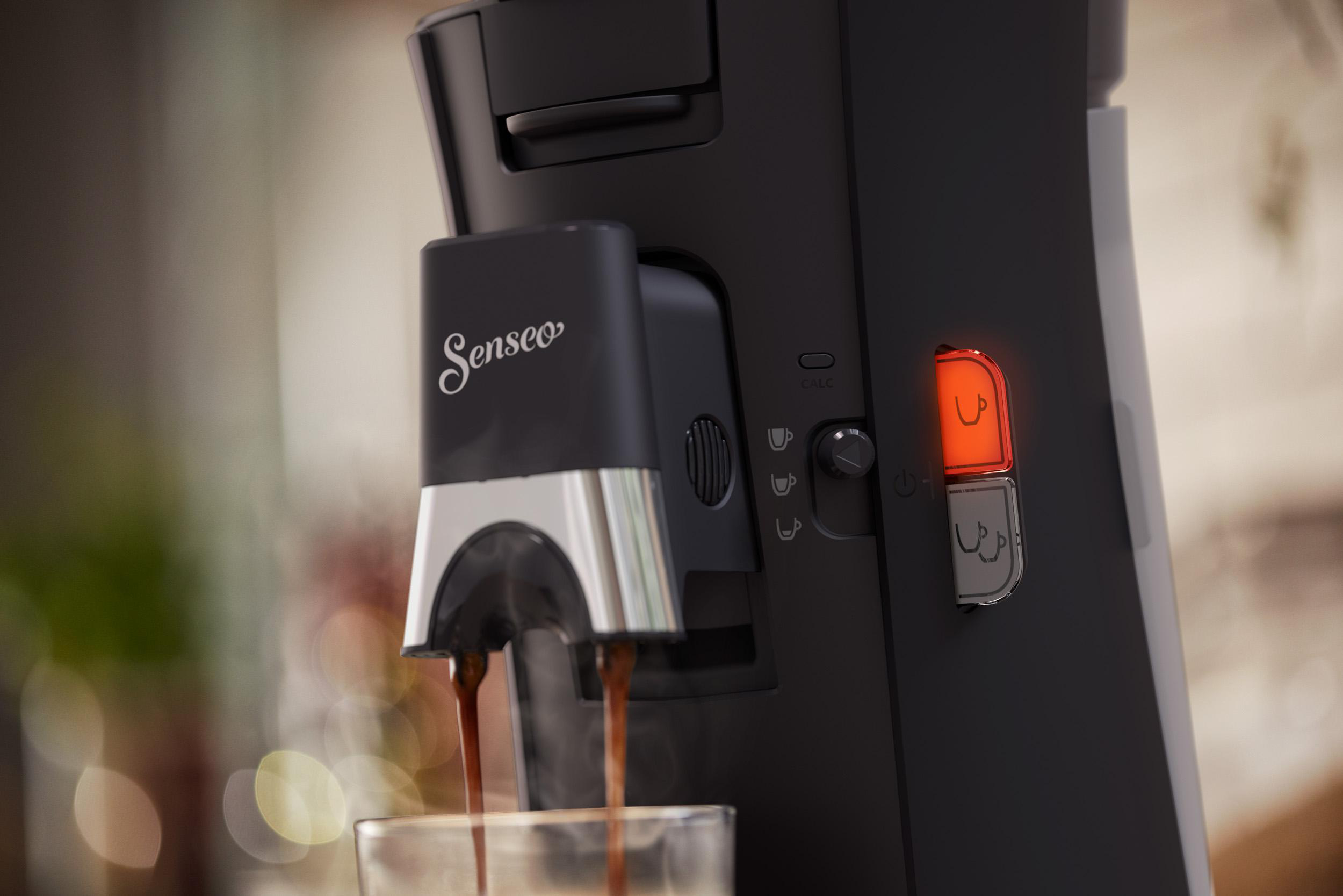 Eine schwarze Kaffeemaschine, die Kaffee in ein Glas ausgibt. Rotes Licht an.