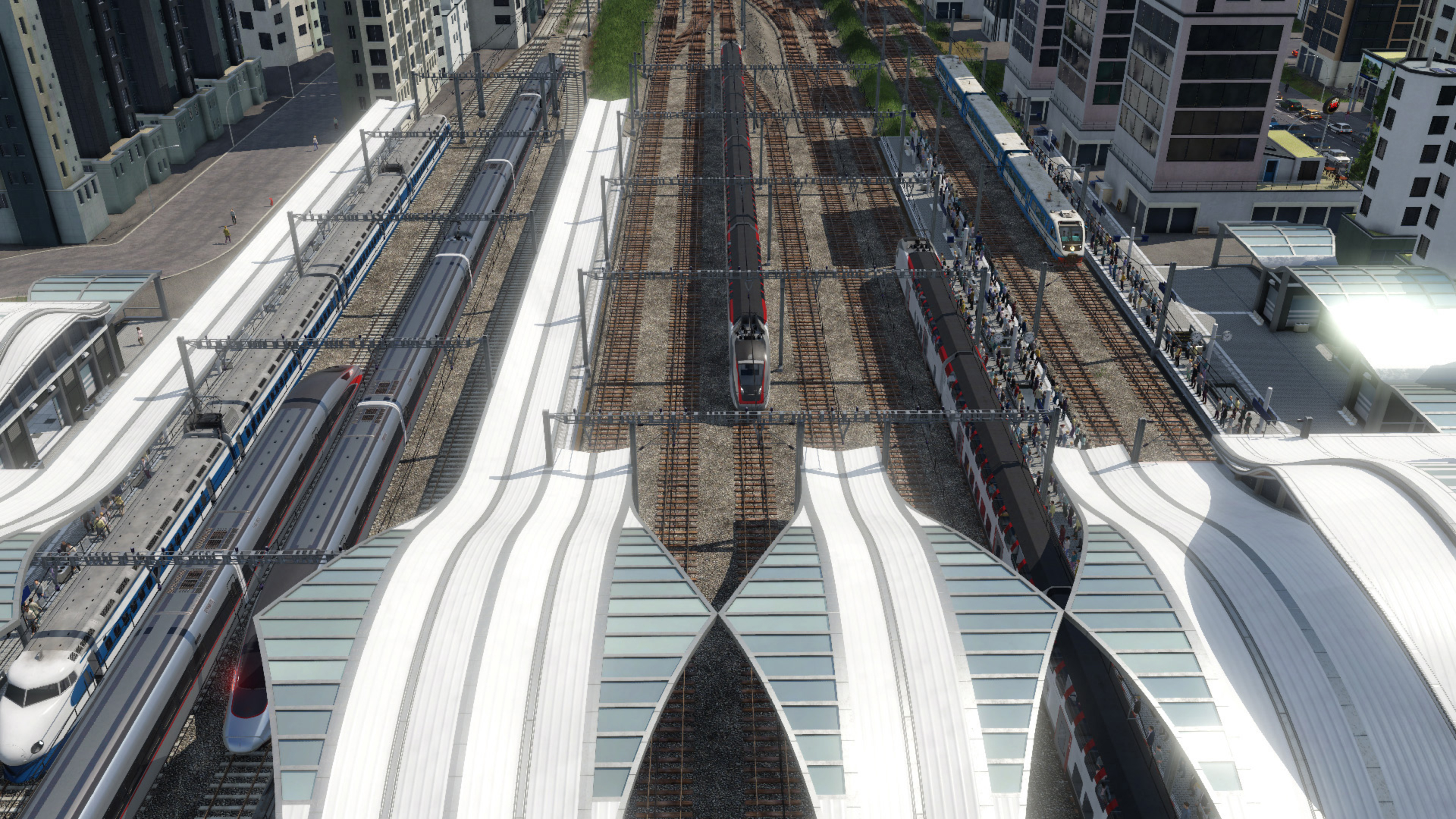 Draufsicht auf einen modernen Bahnhof mit mehreren Gleisen und Zügen.