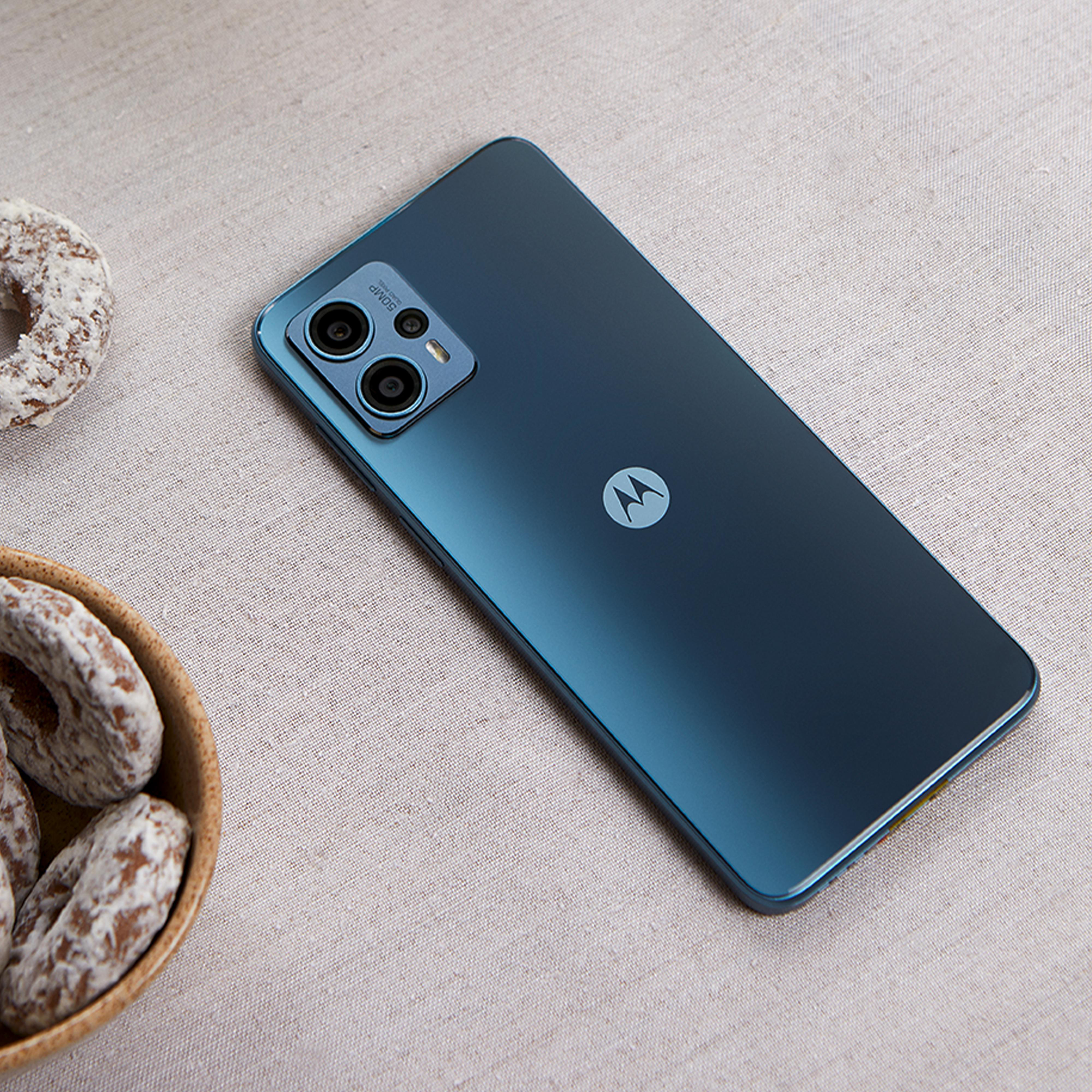 Ein blaues Telefon auf einem Tisch mit einer Schüssel Gebäck. Das Telefon hat ein Motorola-Logo.