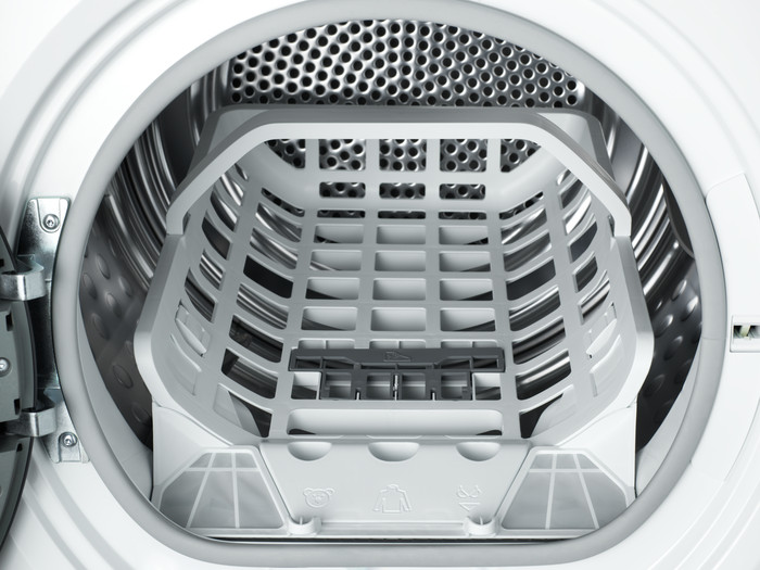 Intérieur d'un tambour de machine à laver avec une grille et des filtres en plastique blanc.