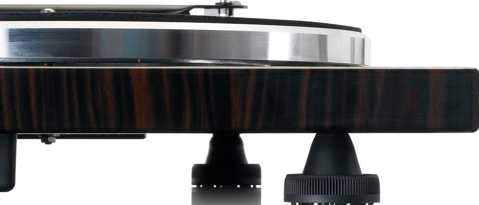 Nahaufnahme eines hölzernen Plattenspielers. Mit schwarzen, kegelförmigen Füßen und einem silbernen Teller.