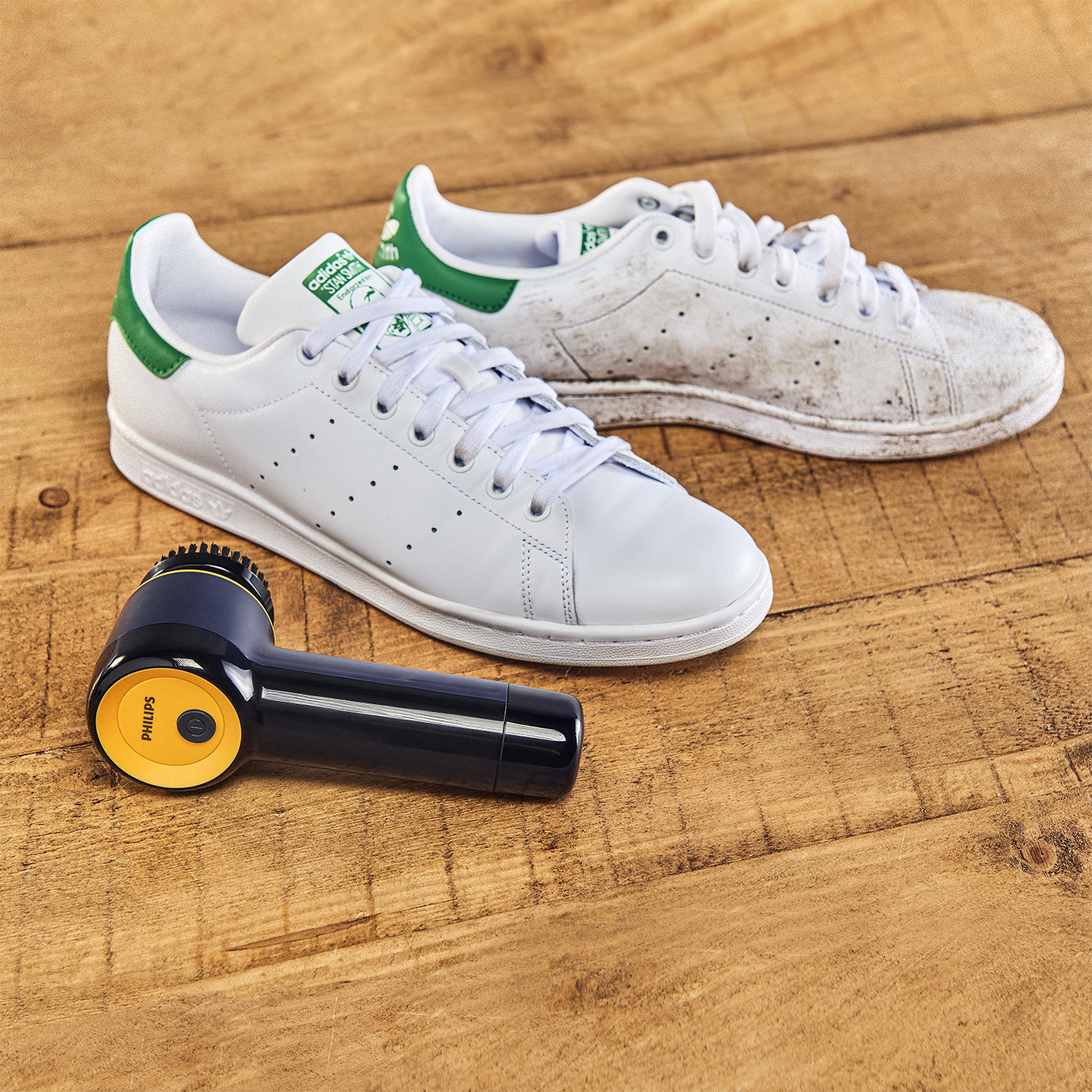 Scarpe Adidas Stan Smith bianche, una sporca, e un pulitore di scarpe.