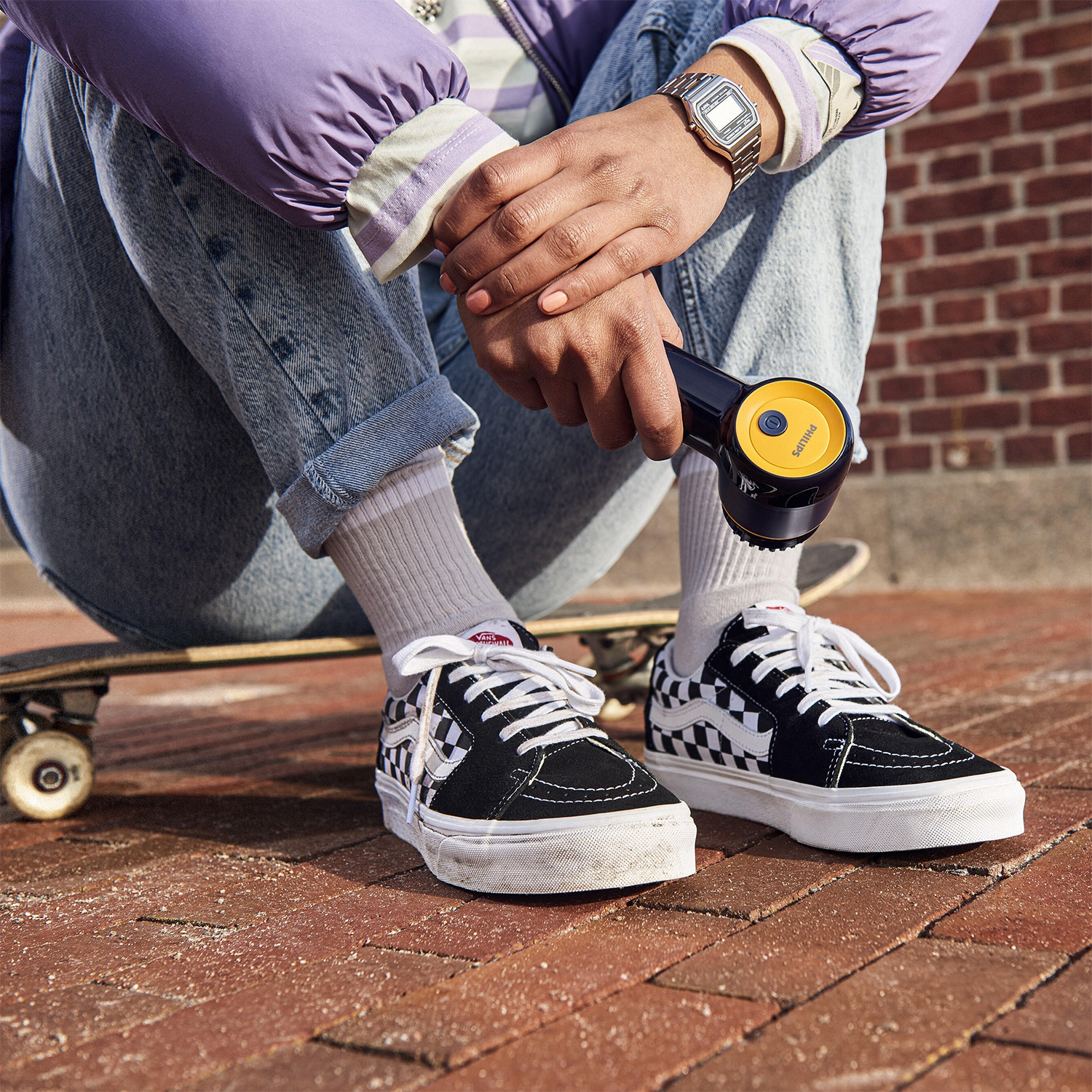 Persona su skateboard che usa una pistola massaggiante nera e gialla.
