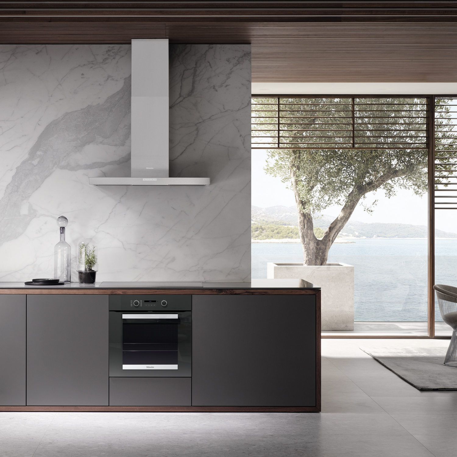 Modern kitchen with a built-in oven, range hood, and a view of the sea.