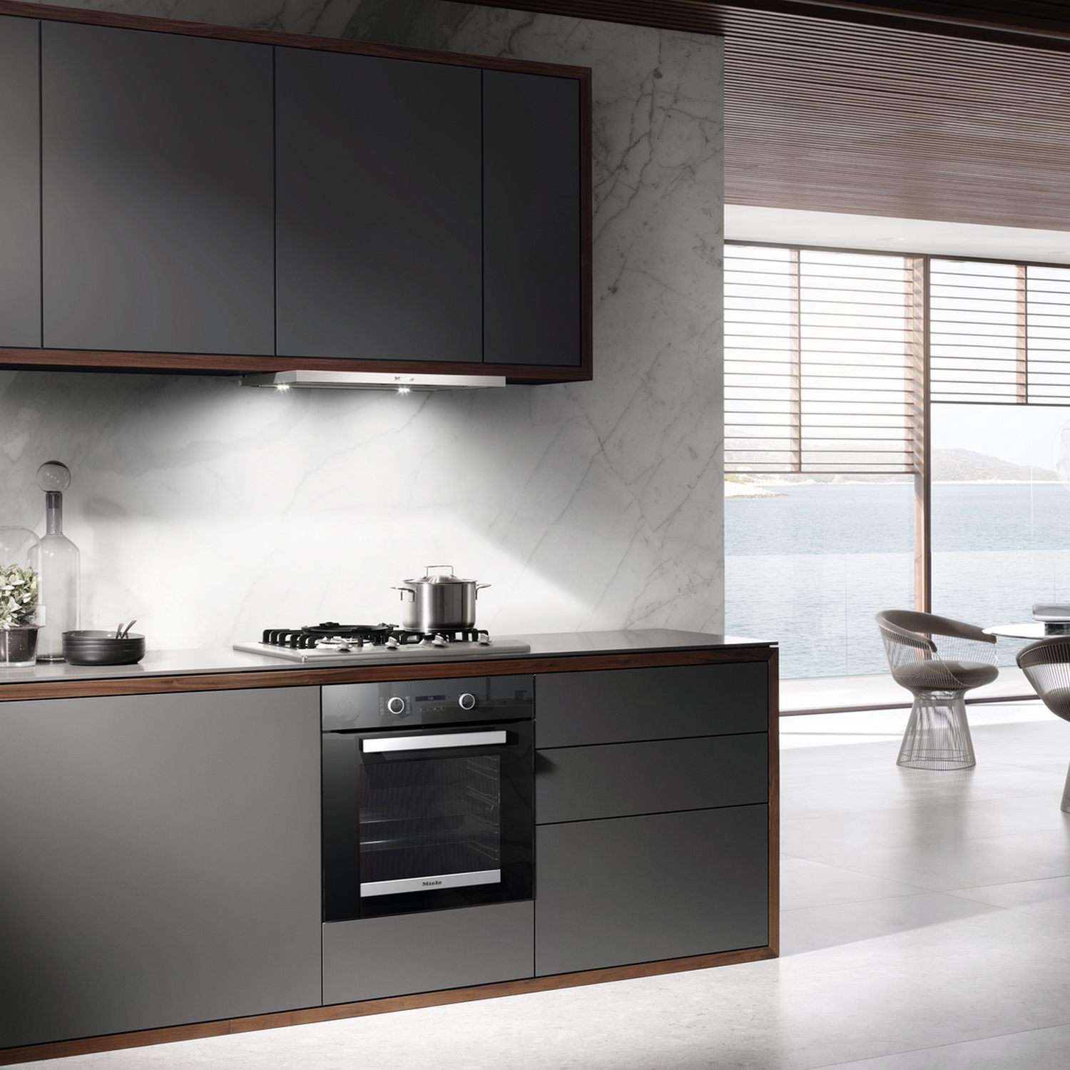 Kitchen with dark gray cabinets, oven, and a stove with a pot.