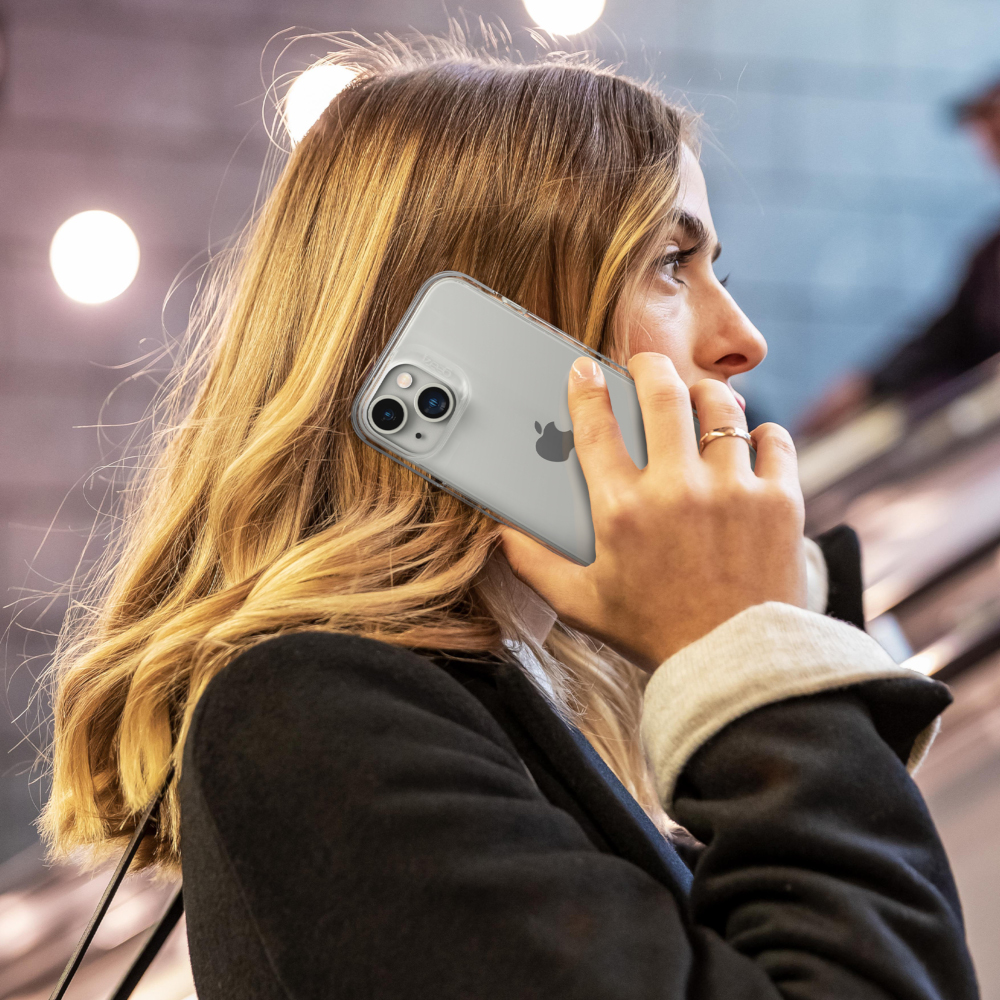 Femme sur un escalator tenant un téléphone dans un étui transparent. Arrière-plan flou.