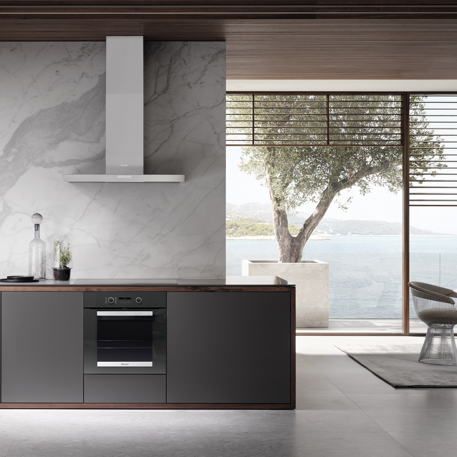 Modern kitchen with sea view, marble wall, extractor hood, and built-in oven.