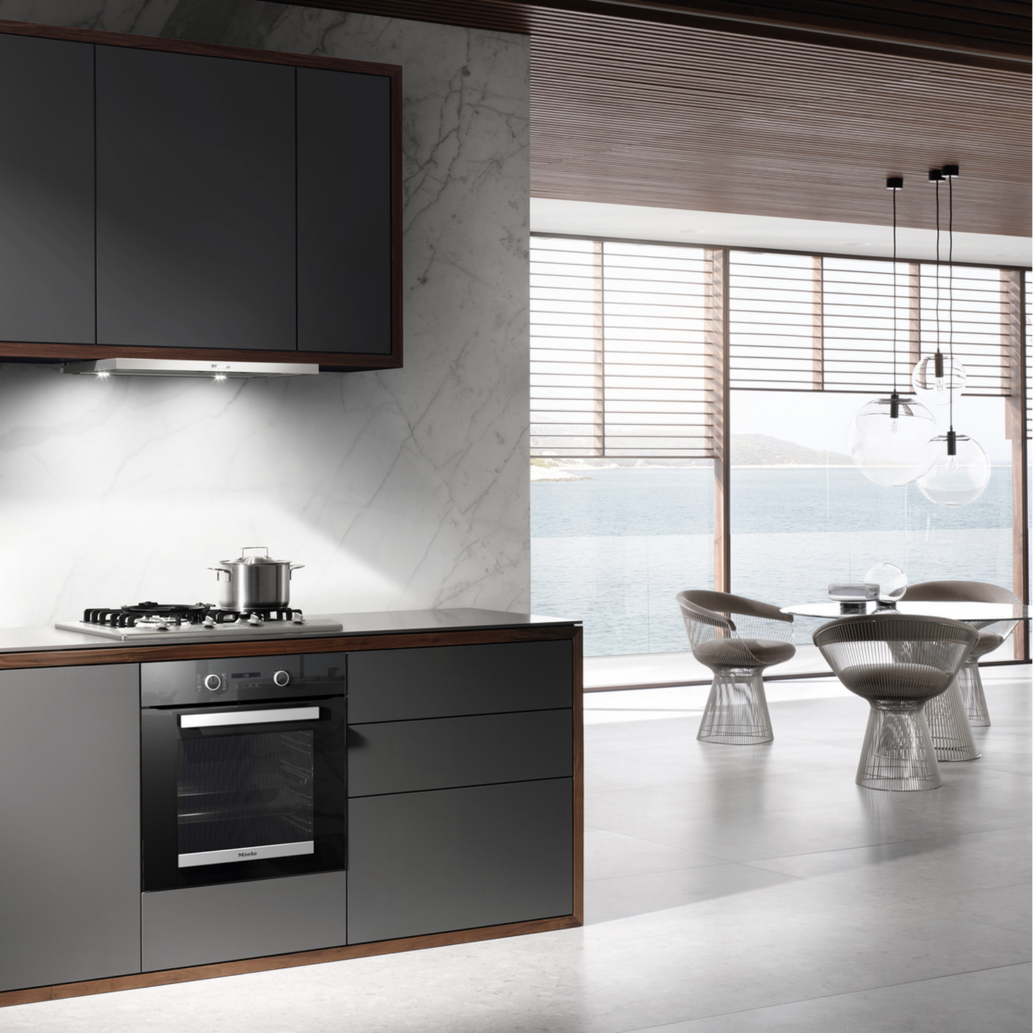 Modern kitchen with dark cabinets, oven, stove, and a sea view.