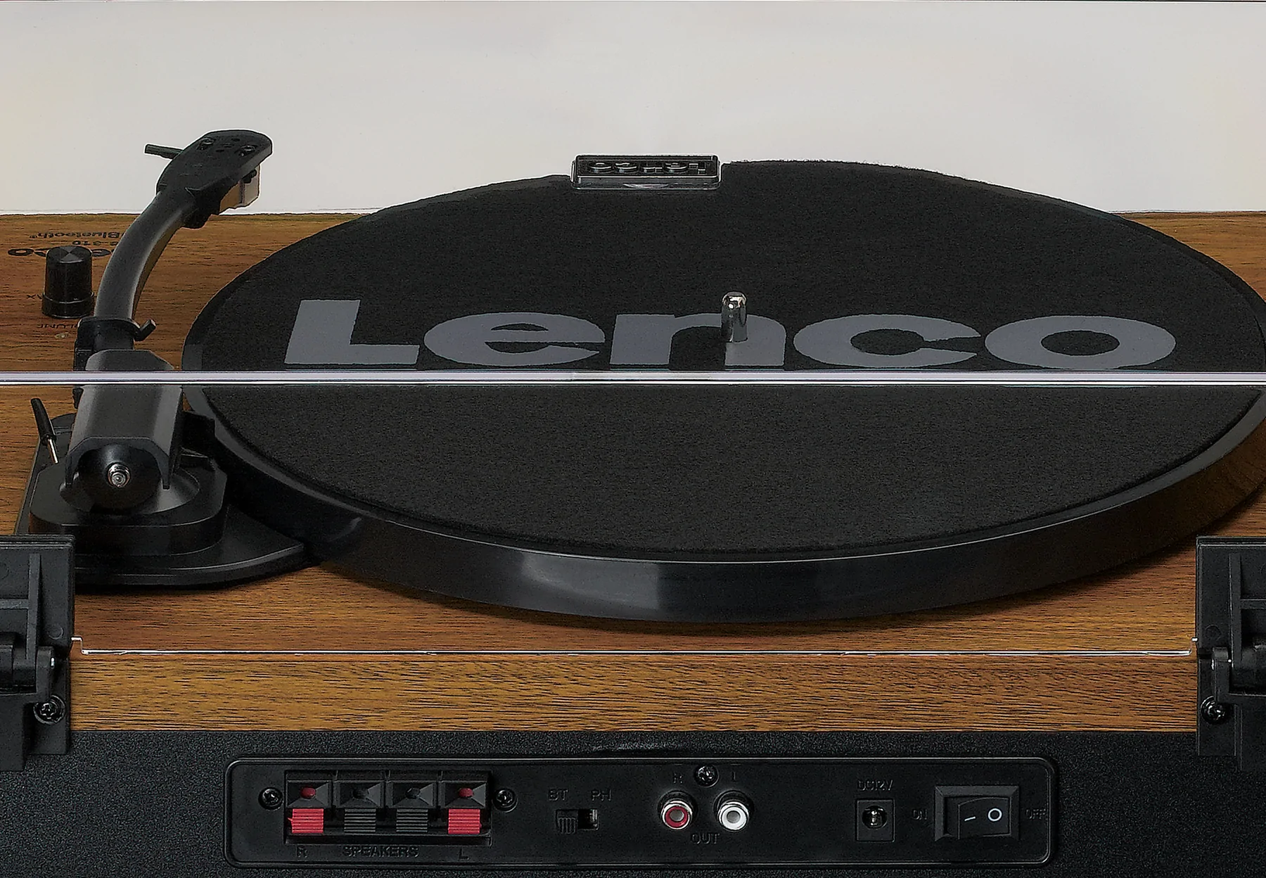 Platine vinyle avec disque noir, corps en bois et commandes. Fond uni.