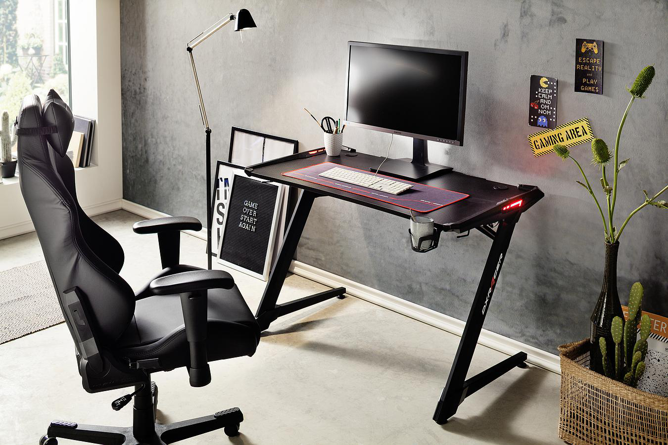 Gaming-Setup mit schwarzem Stuhl, Schreibtisch und Monitor.