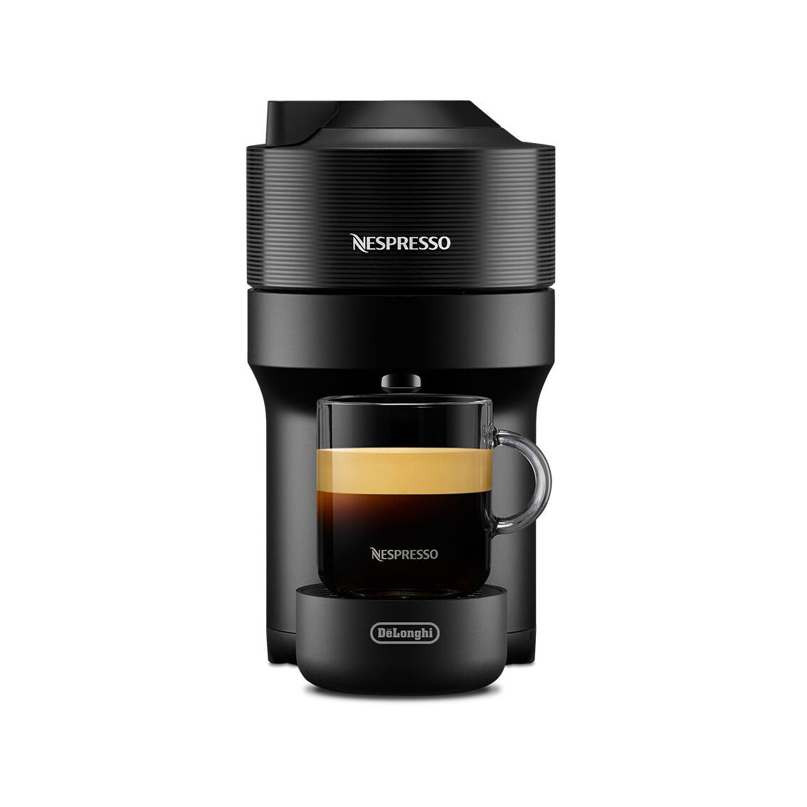 Schwarze Nespresso-Kaffeemaschine mit einem Glas Kaffee auf schwarzem Sockel.