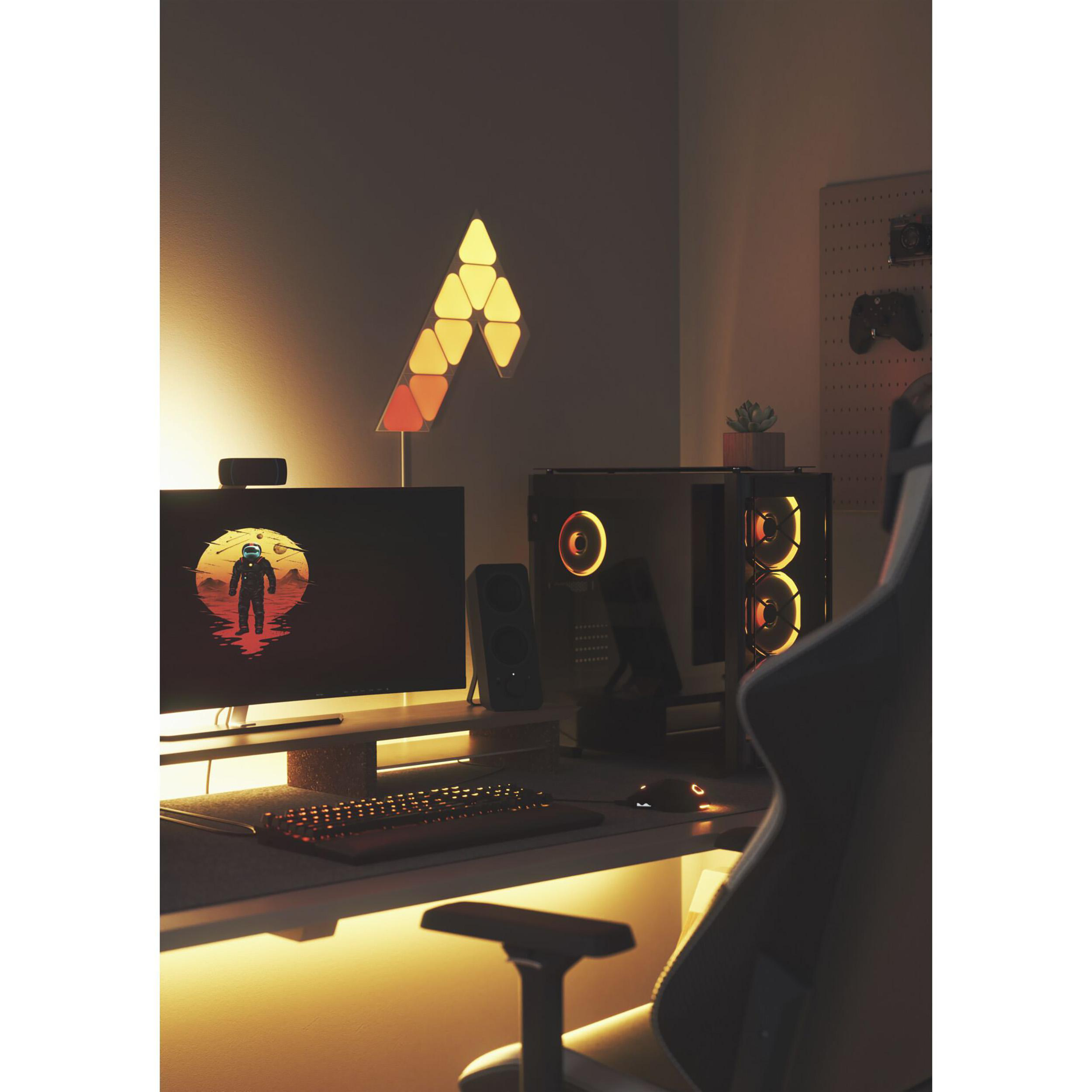 Gemütliches Gaming-Setup. Computer, Lichter und Schreibtisch mit Stuhl im Vordergrund.