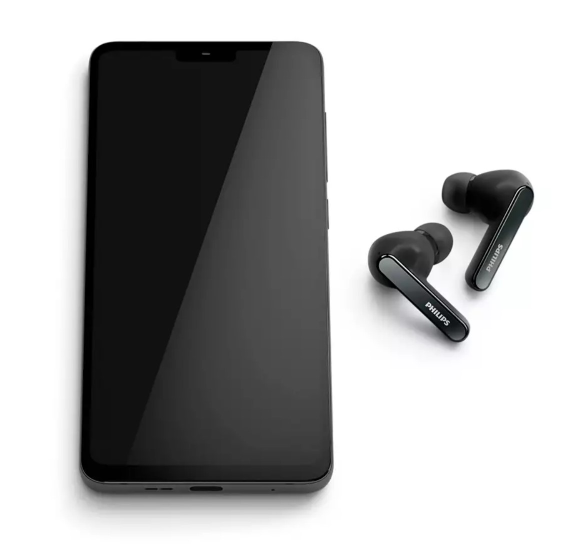 Siyah bir akıllı telefonun yanında siyah Philips kulaklıklar. Telefon ekranı karanlık.