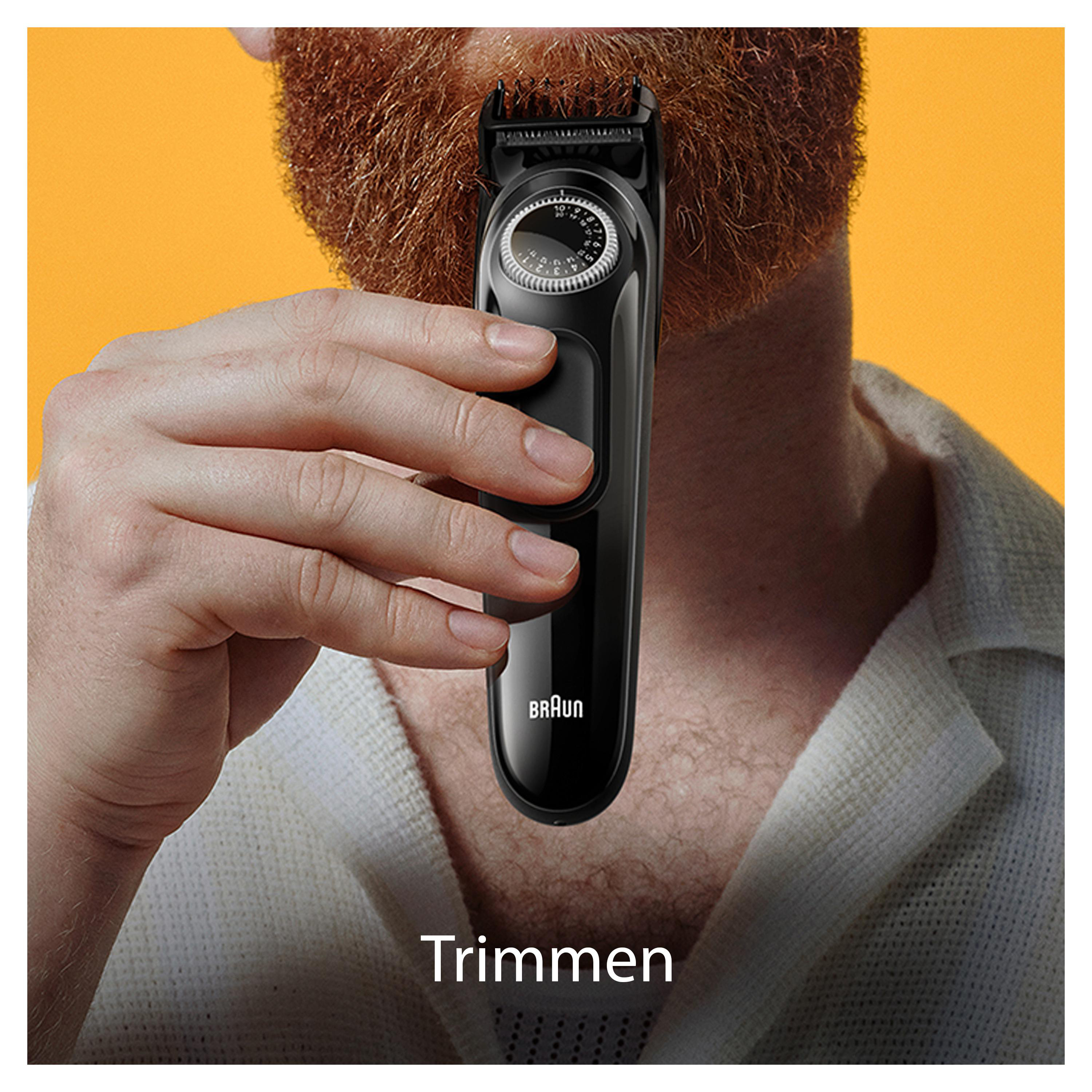 Mann, der seinen Bart mit einem schwarzen Braun-Trimmer trimmt. Oranger Hintergrund ist sichtbar.