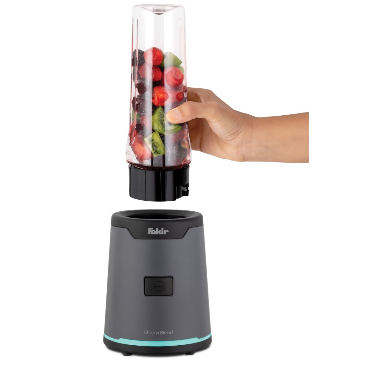 Bir el, gri bir tabanın üzerinde meyve dolu bir blender kabını tutuyor.