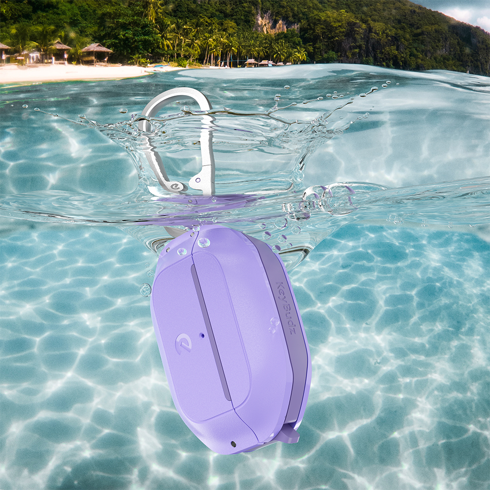 Lila KeyBudz schwebt im Wasser mit Karabiner. Tropischer Strandhintergrund mit klarem Wasser und Himmel.