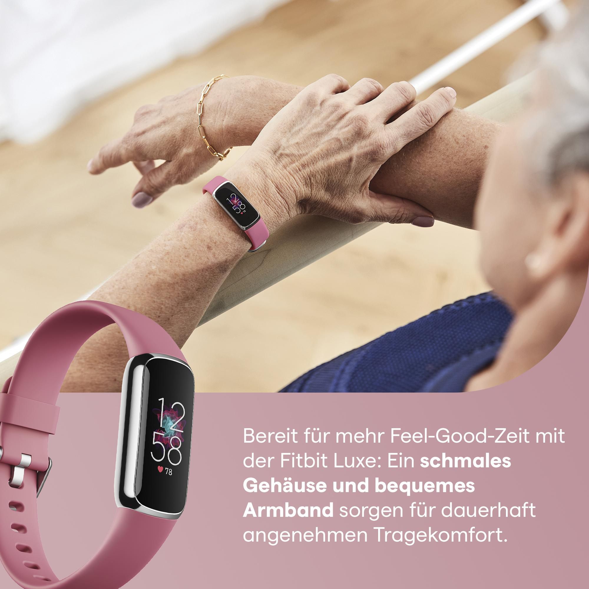 Eine pinke Fitbit-Uhr am Handgelenk einer Frau und eine weitere auf einem Tisch mit Text.