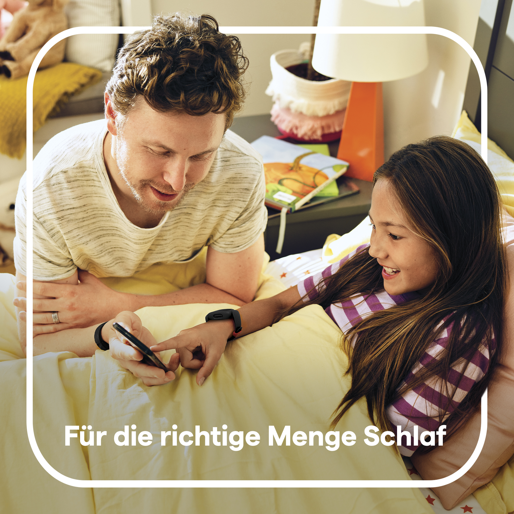 Vater und Tochter schauen auf ein Telefon. Sie sind im Bett. Text deutet auf Schlafüberwachung hin.