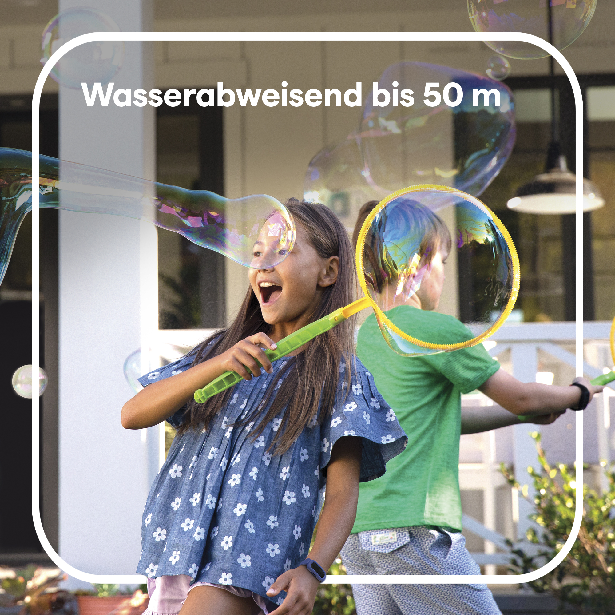 Zwei Kinder spielen draußen mit Seifenblasen, mit einem Haus im Hintergrund, Blasen fliegen.
