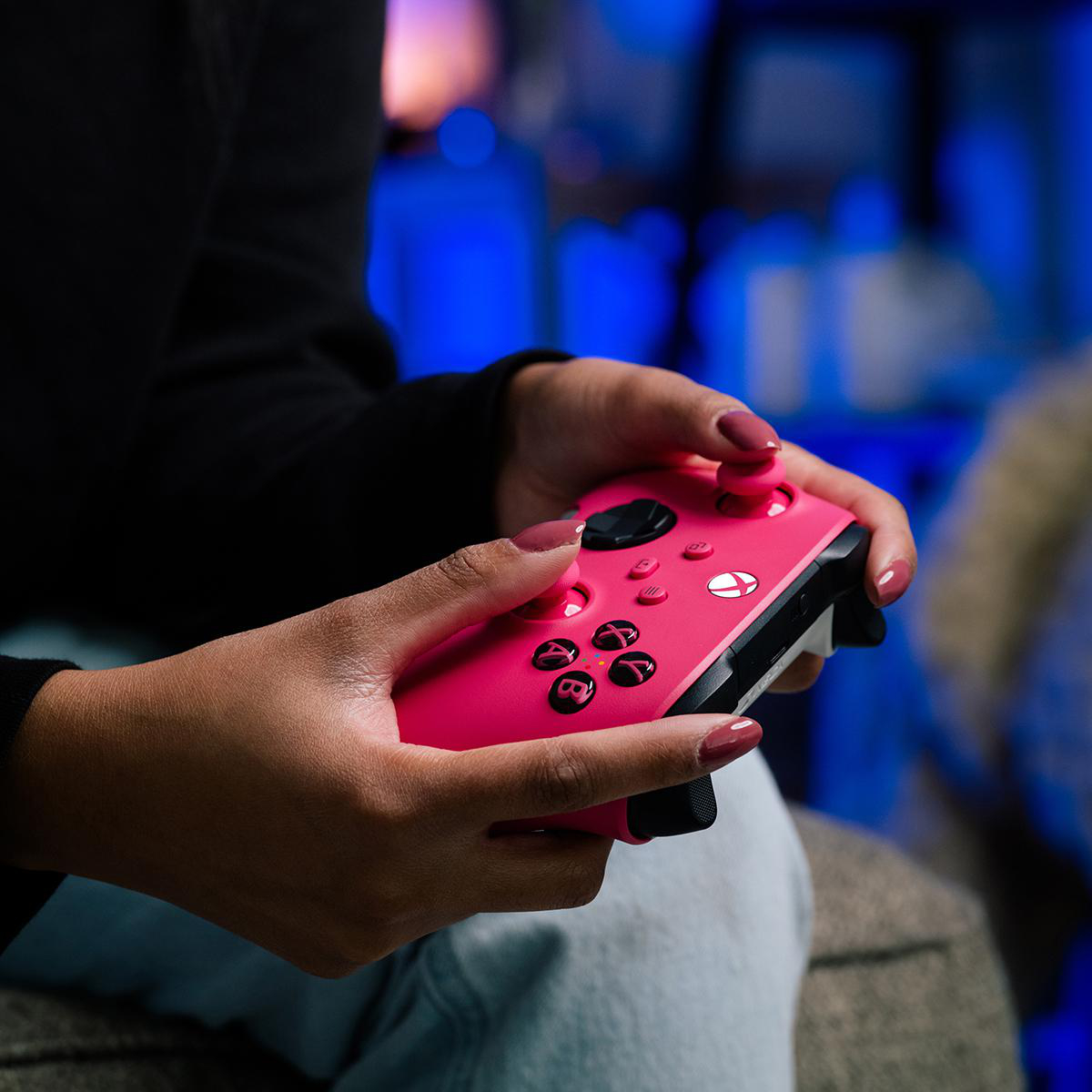 Eine Person hält einen rosafarbenen Controller. Der Controller hat schwarze Knöpfe und weißes Xbox-Logo.