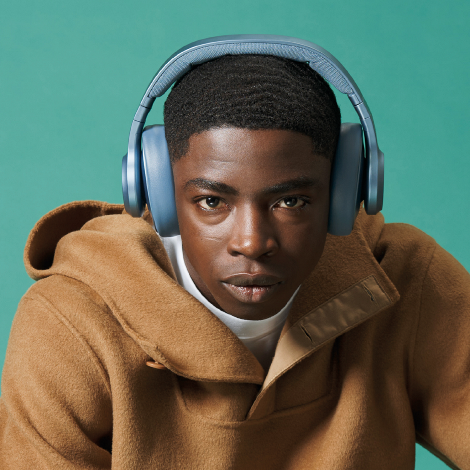 Black man wearing blue headphones, looking at camera.