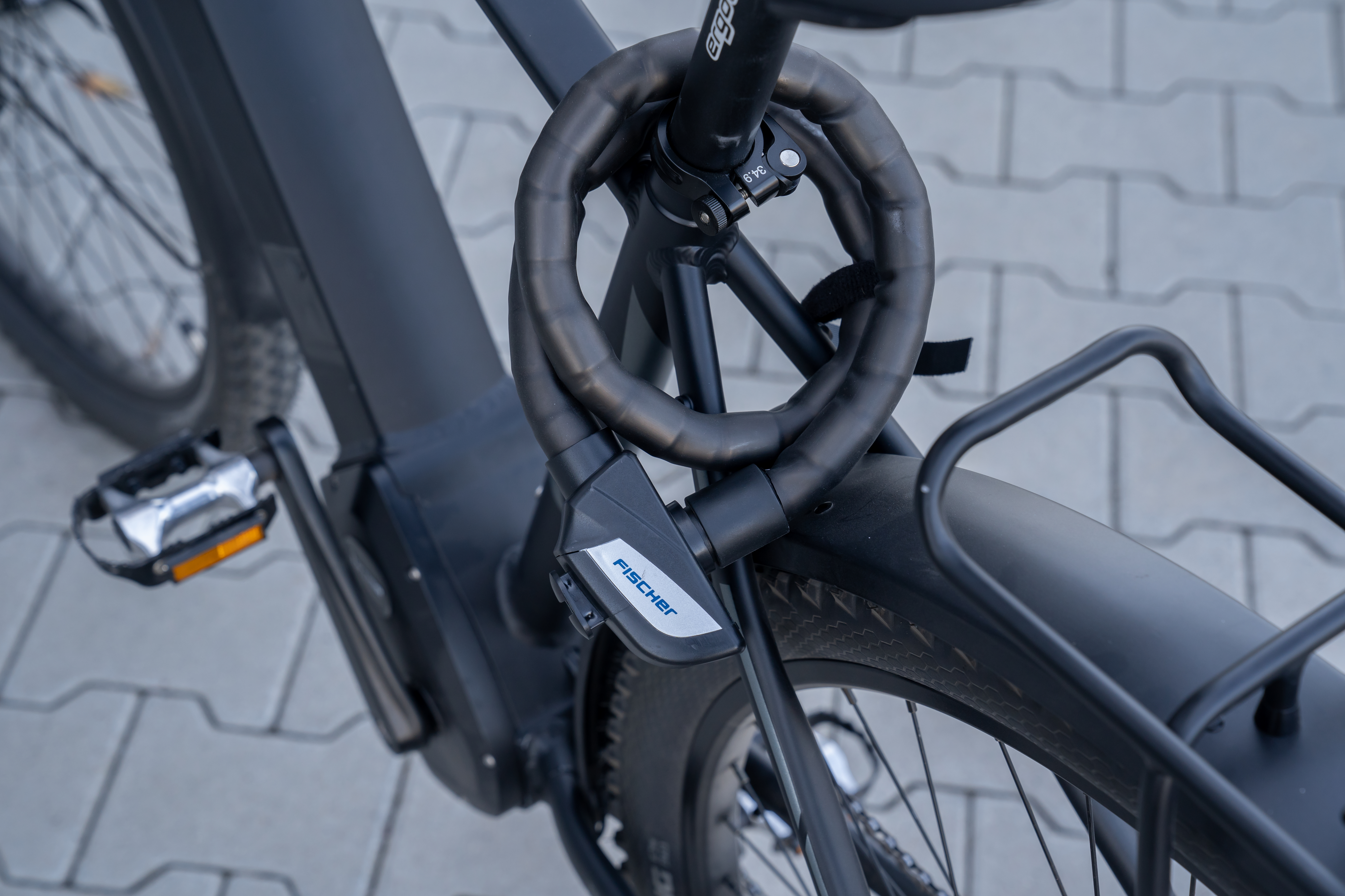Schwarzes Fahrrad mit FISCHER-Schloss, das Hinterrad und Rahmen sichert.