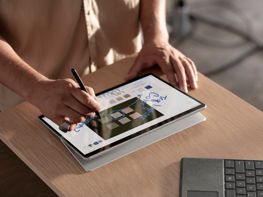 A person uses a stylus to write on a tablet. The screen shows a diagram.