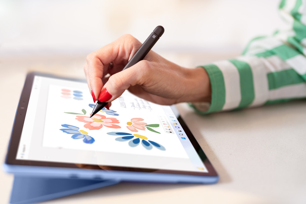 A person drawing flowers on a tablet with a stylus.