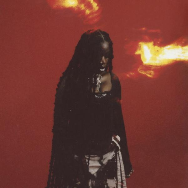 Une femme en robe noire avec de longs cheveux tressés se tient devant un fond rouge.