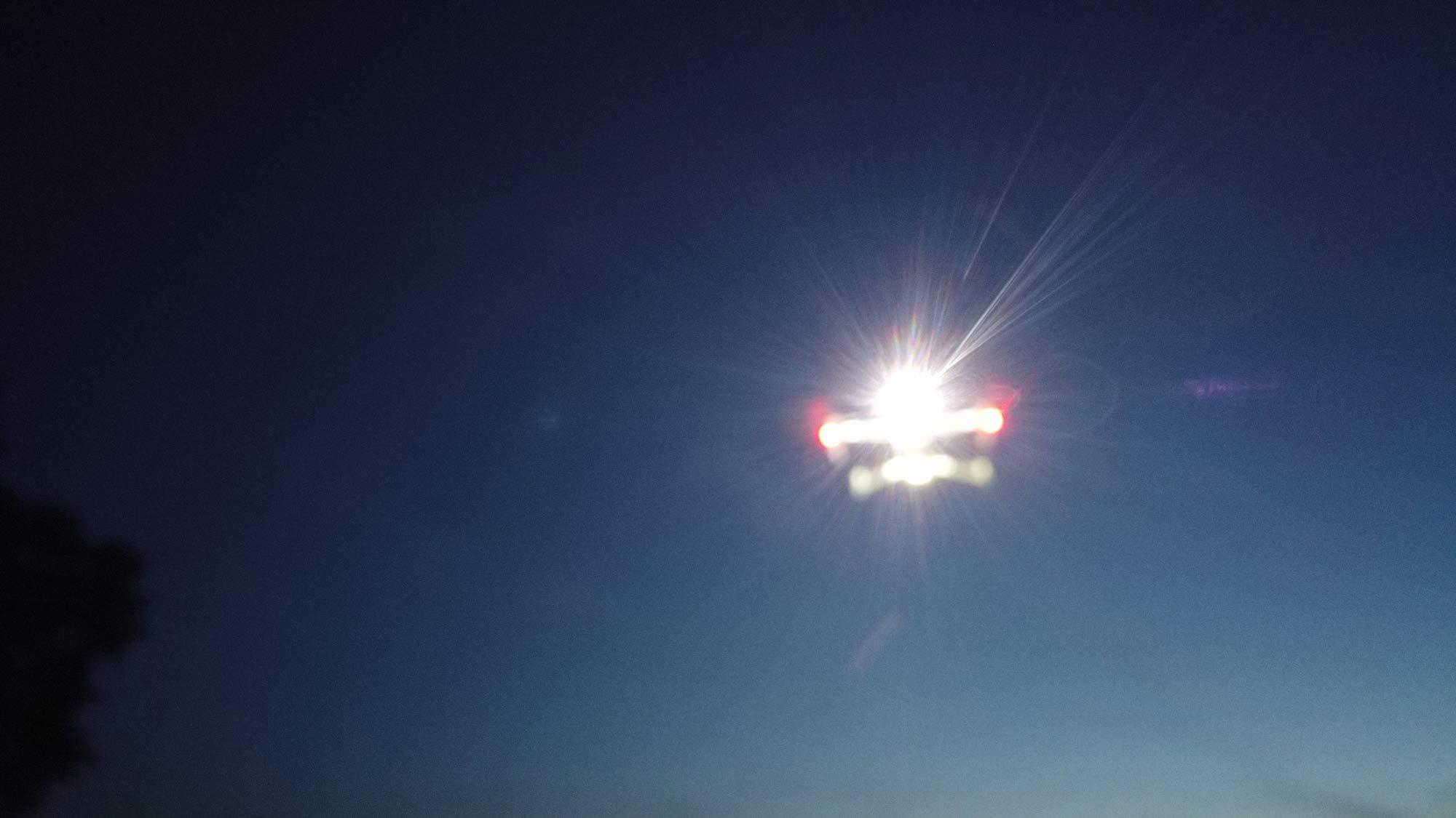 Helle Sonne scheint in einem dunkelblauen Himmel mit einem Hauch von Rot.