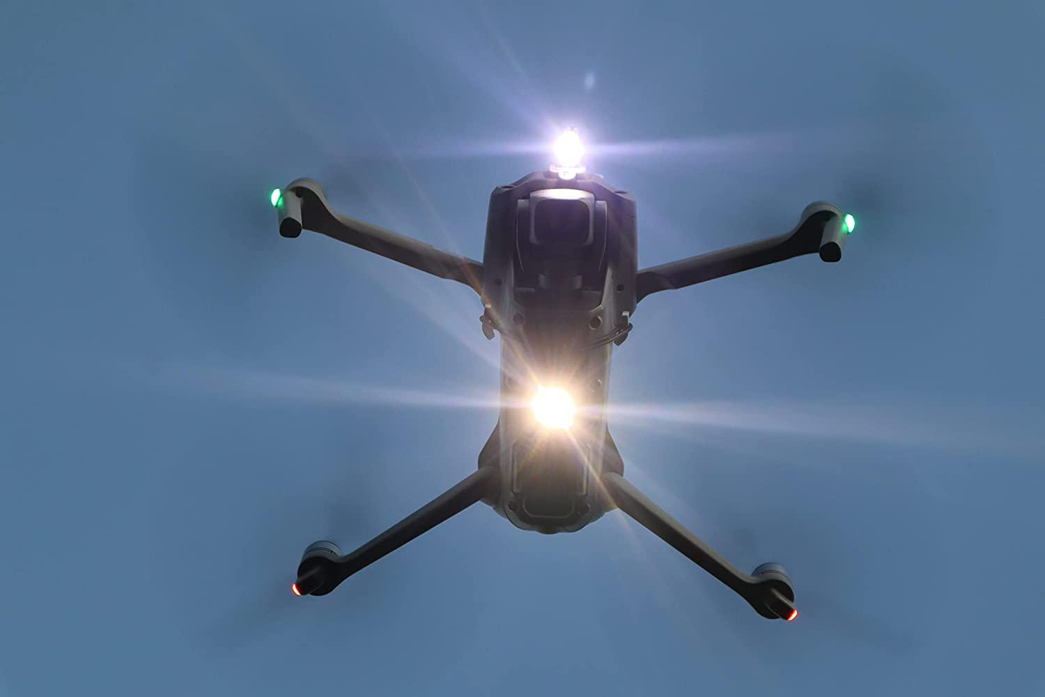 Drohne fliegt am Himmel, helles Licht scheint, vier Propeller sichtbar.