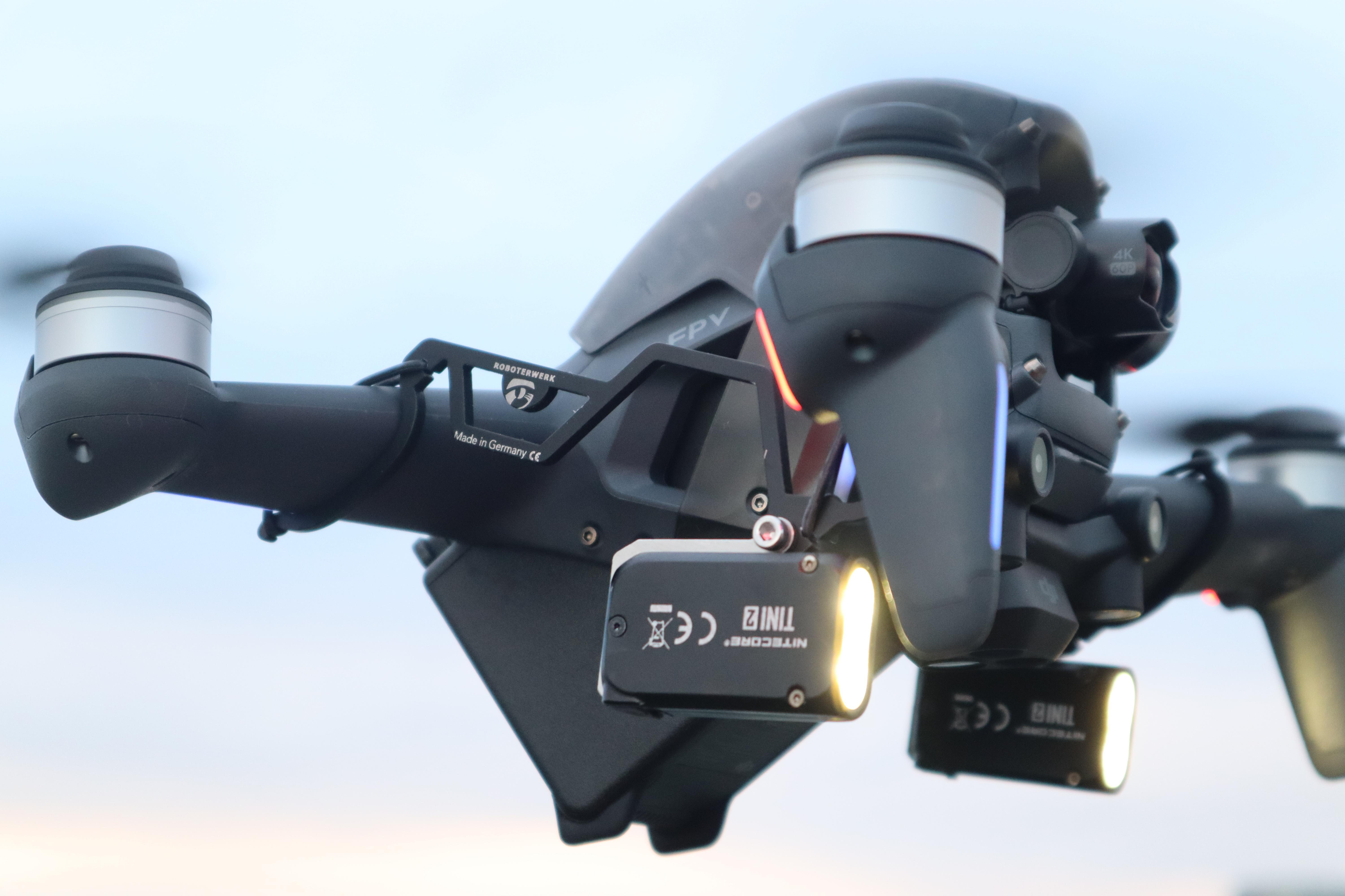 Schwarze Drohne mit Lichtern, die am Himmel fliegt. Dunkler Hintergrund.