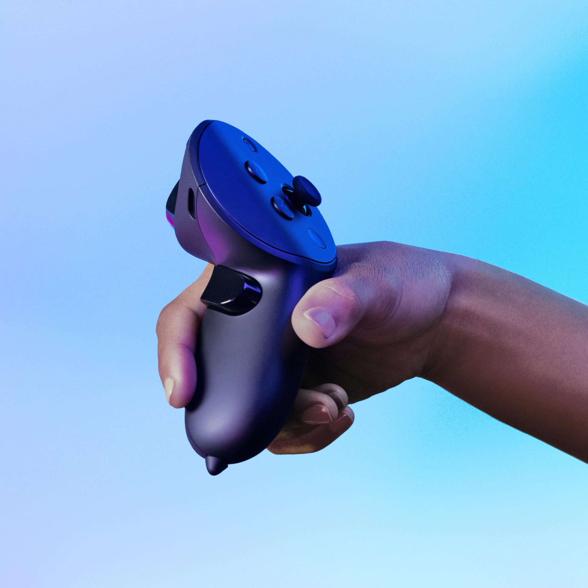 Eine Hand hält einen dunkel gefärbten VR-Controller vor blauem Farbverlauf.