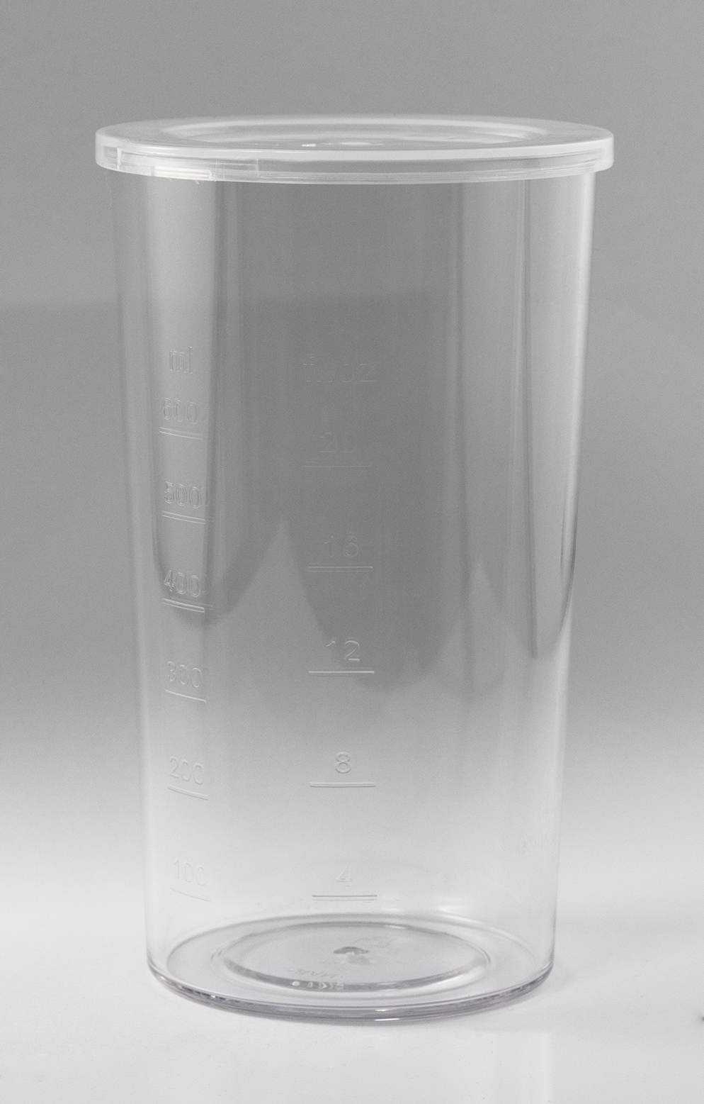 Un vaso medidor cilíndrico transparente con marcas de volumen y tapa.