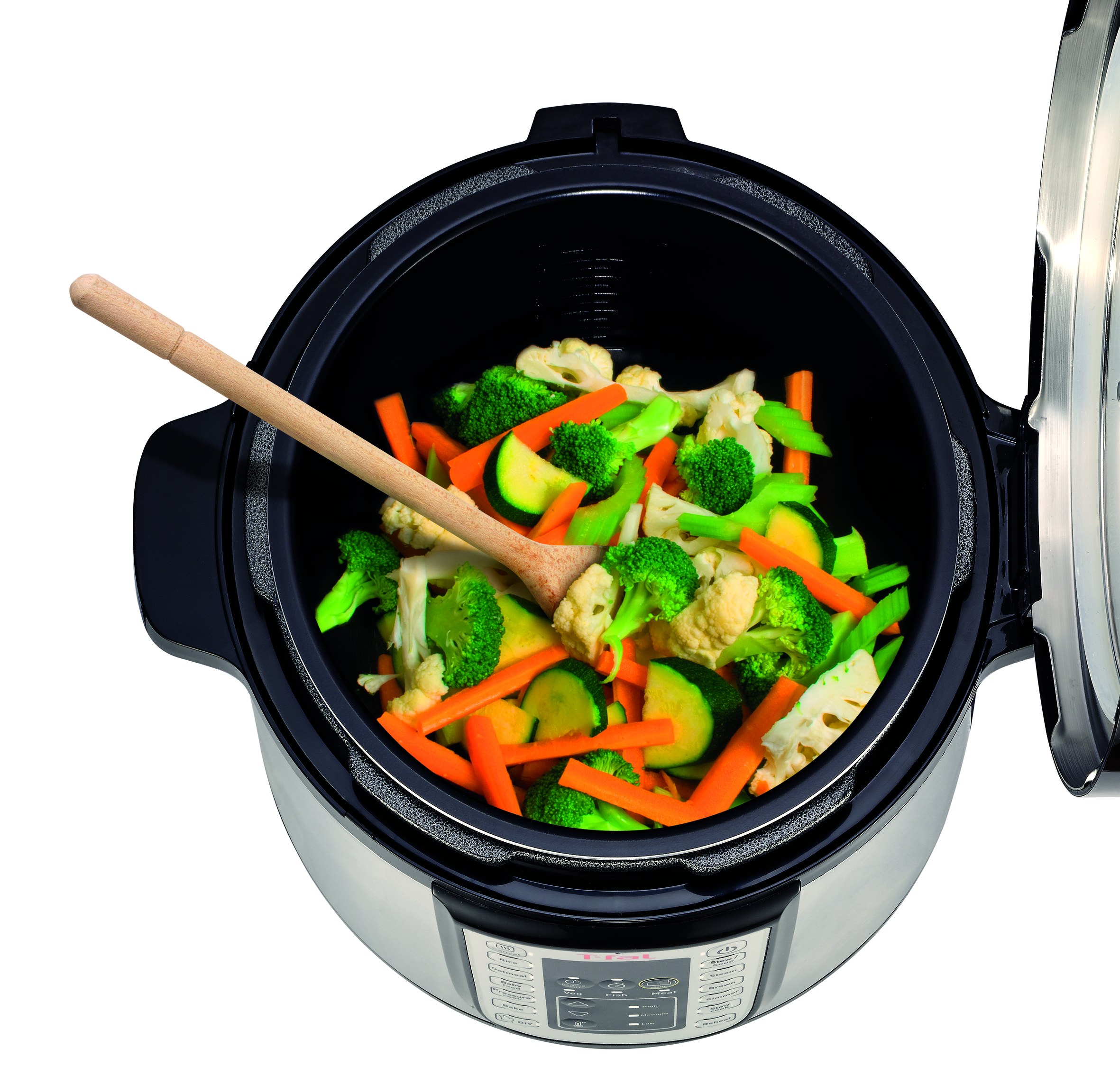 Una olla a presión abierta con verduras cocidas dentro, una cuchara de madera encima.