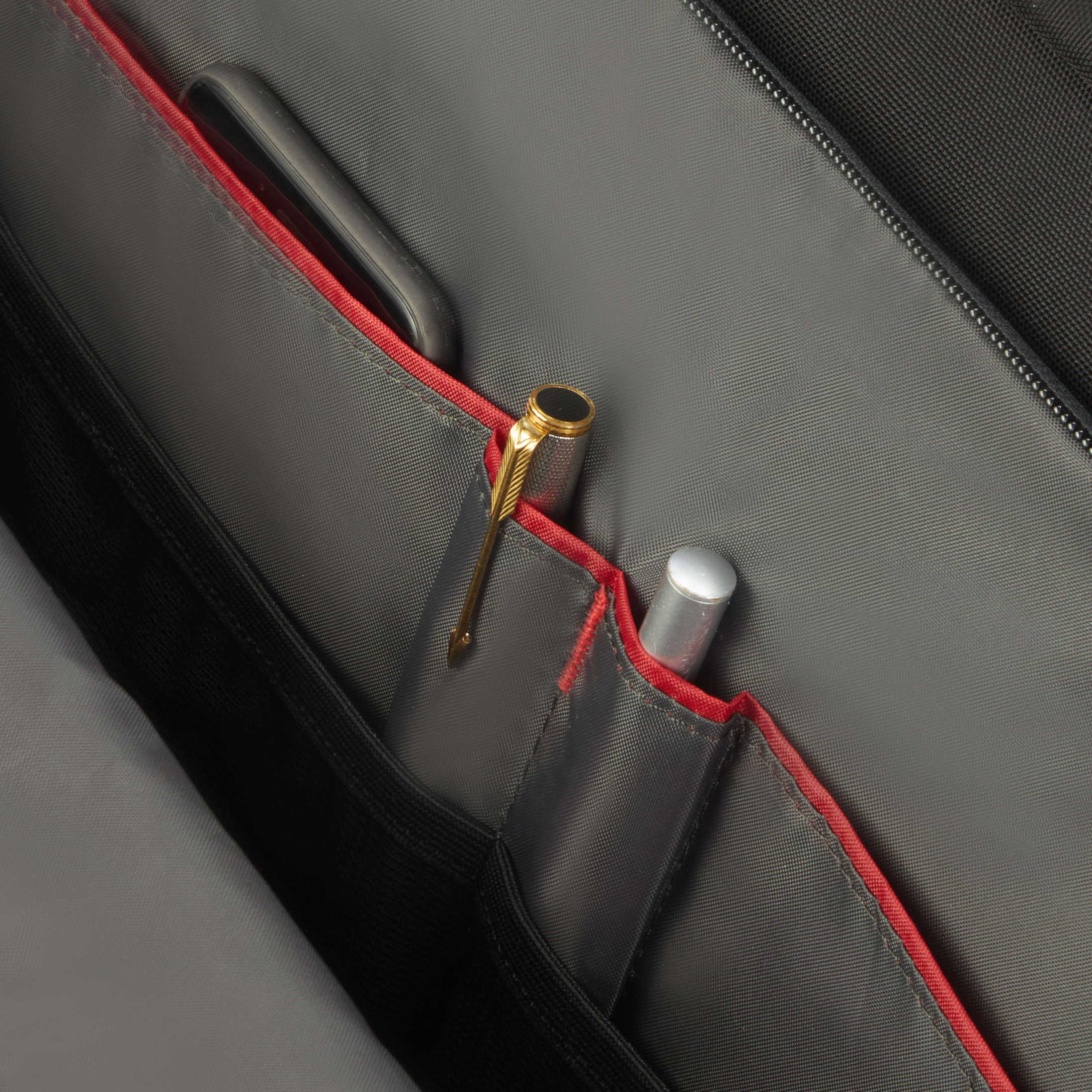 In einer Tasche, offene Taschen mit einem Stift und einem anderen silbernen Objekt, rotes Futter.
