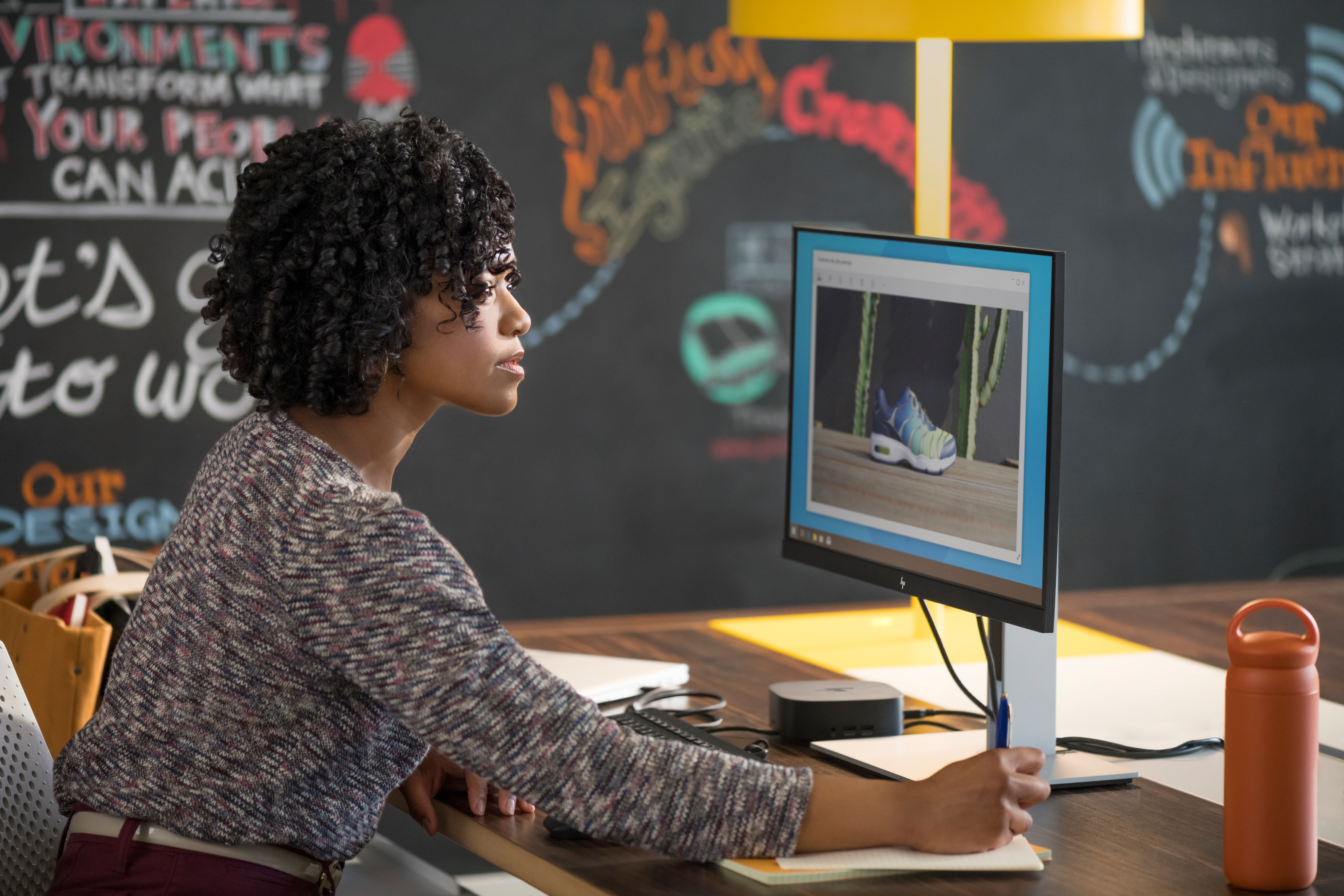 Frau schaut auf Computerbildschirm mit Schuhbild. Dunkler Hintergrund.