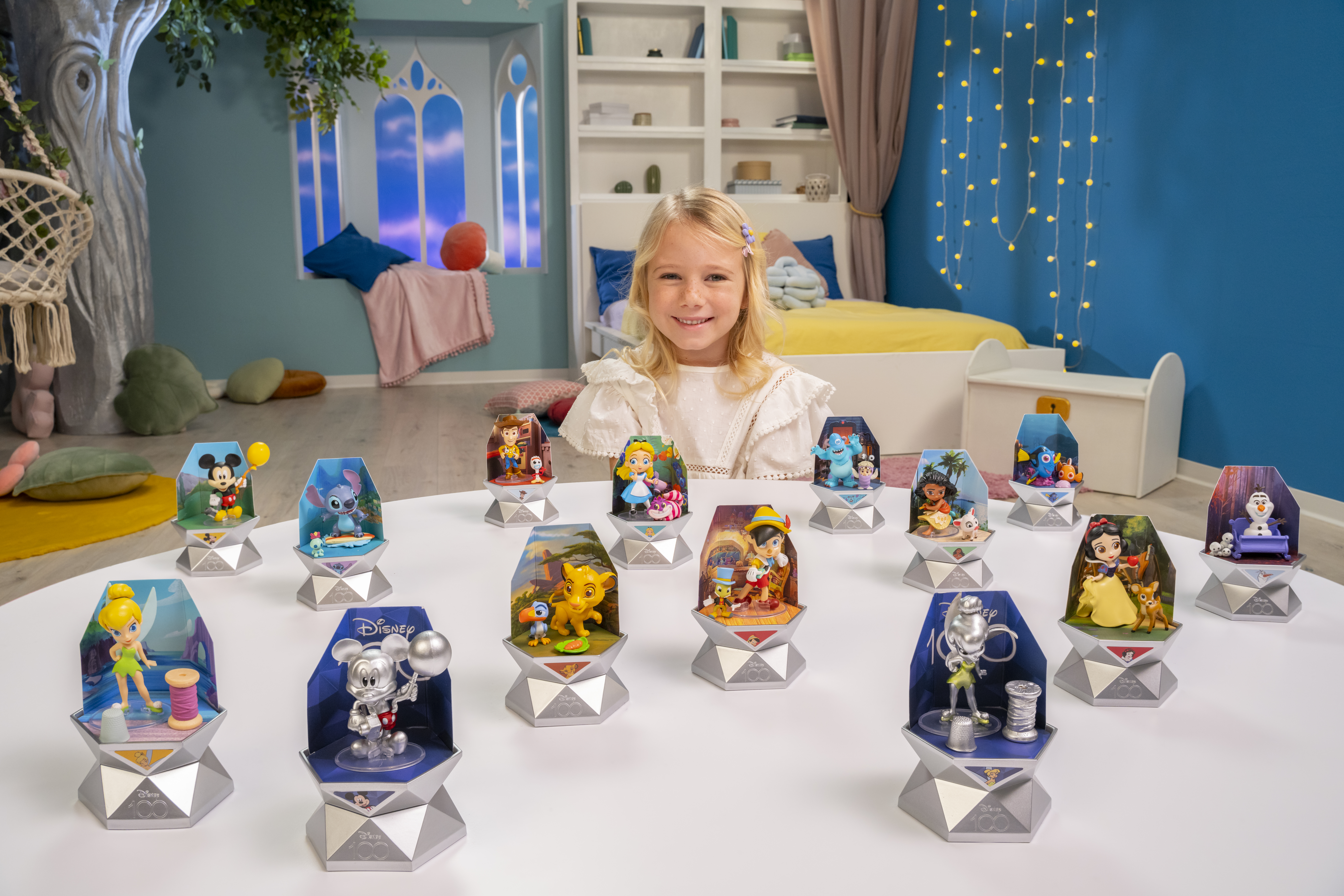 Ein Mädchen mit Disney-Figuren auf einem Tisch. Es gibt verschiedene Disney-Figuren.