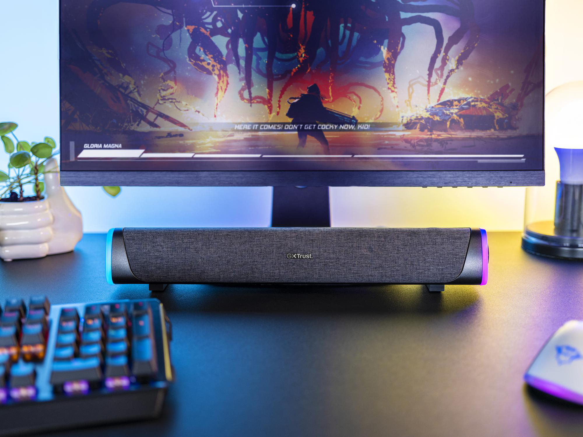 Eine schwarze GXT-Soundbar mit RGB-Beleuchtung steht auf einem Schreibtisch vor einem Monitor und einer Tastatur.