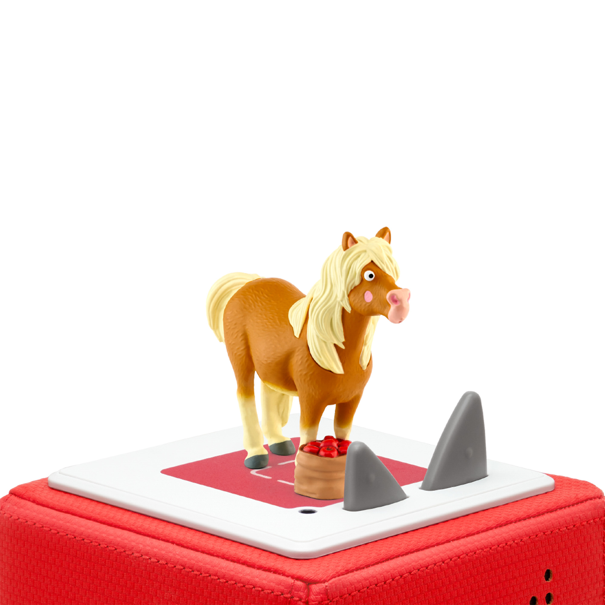 Ein Spielzeugpferd mit einem Wagen voller Kirschen auf einem roten Quadrat. Zwei graue Haifischflossen.