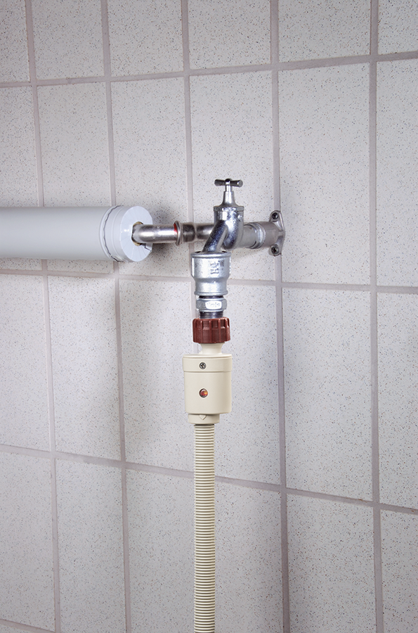 Faucet and water hose connected to a tiled wall, with a brown connector.