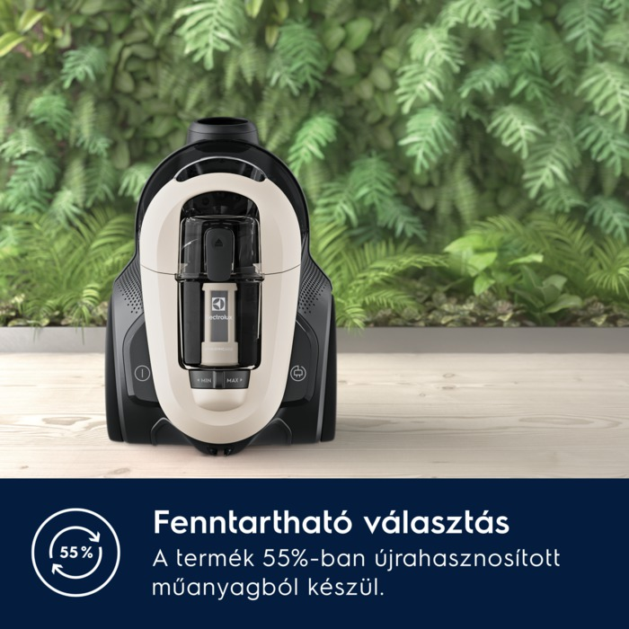 Egy fekete-fehér porszívó egy fa felületen, növényekkel a háttérben.