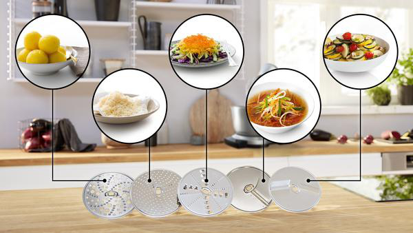 Küchenszene mit Schalen mit Essen, Klingen und einem Mixer. Verschiedene Zutaten sind ebenfalls vorhanden.