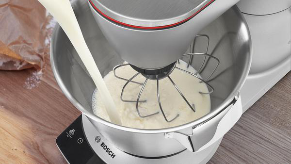 Ein Mixer gießt Milch in die Schüssel, Sahne ist drin.